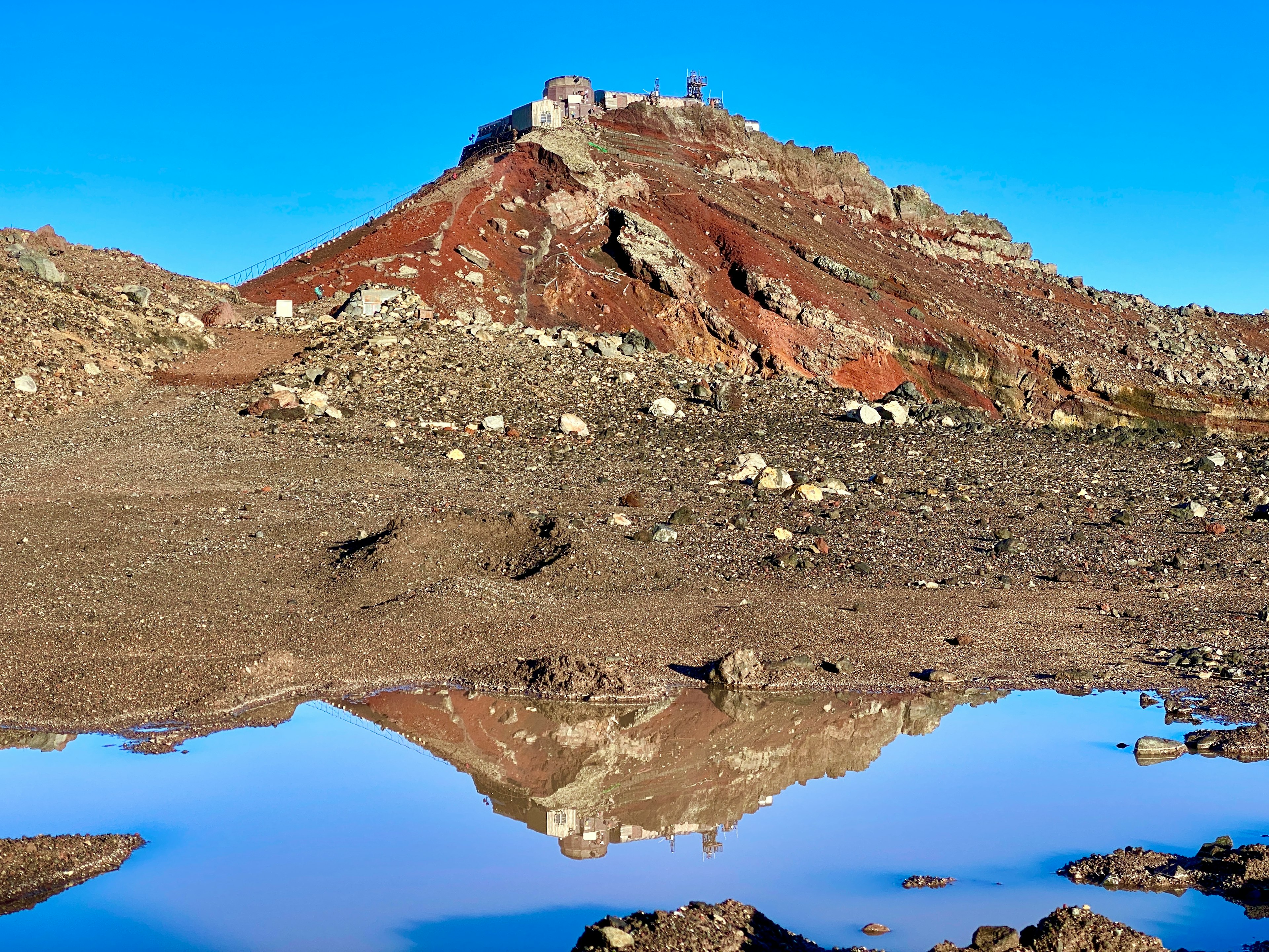 Malersicher Ausblick auf einen roten Berg mit Spiegelung in einer Pfütze