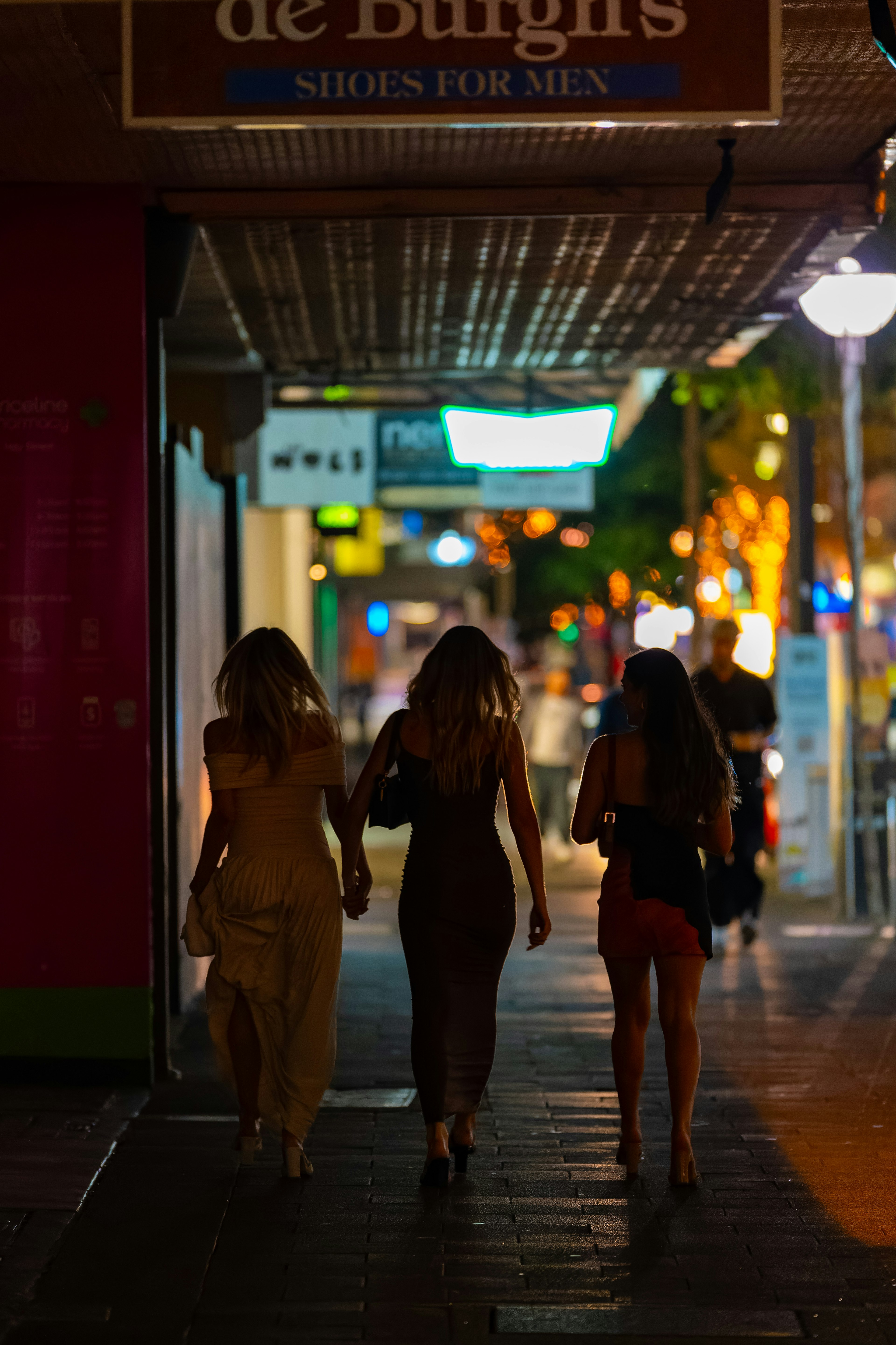 夜の街を歩く三人の女性のシルエットと明るいネオンの背景