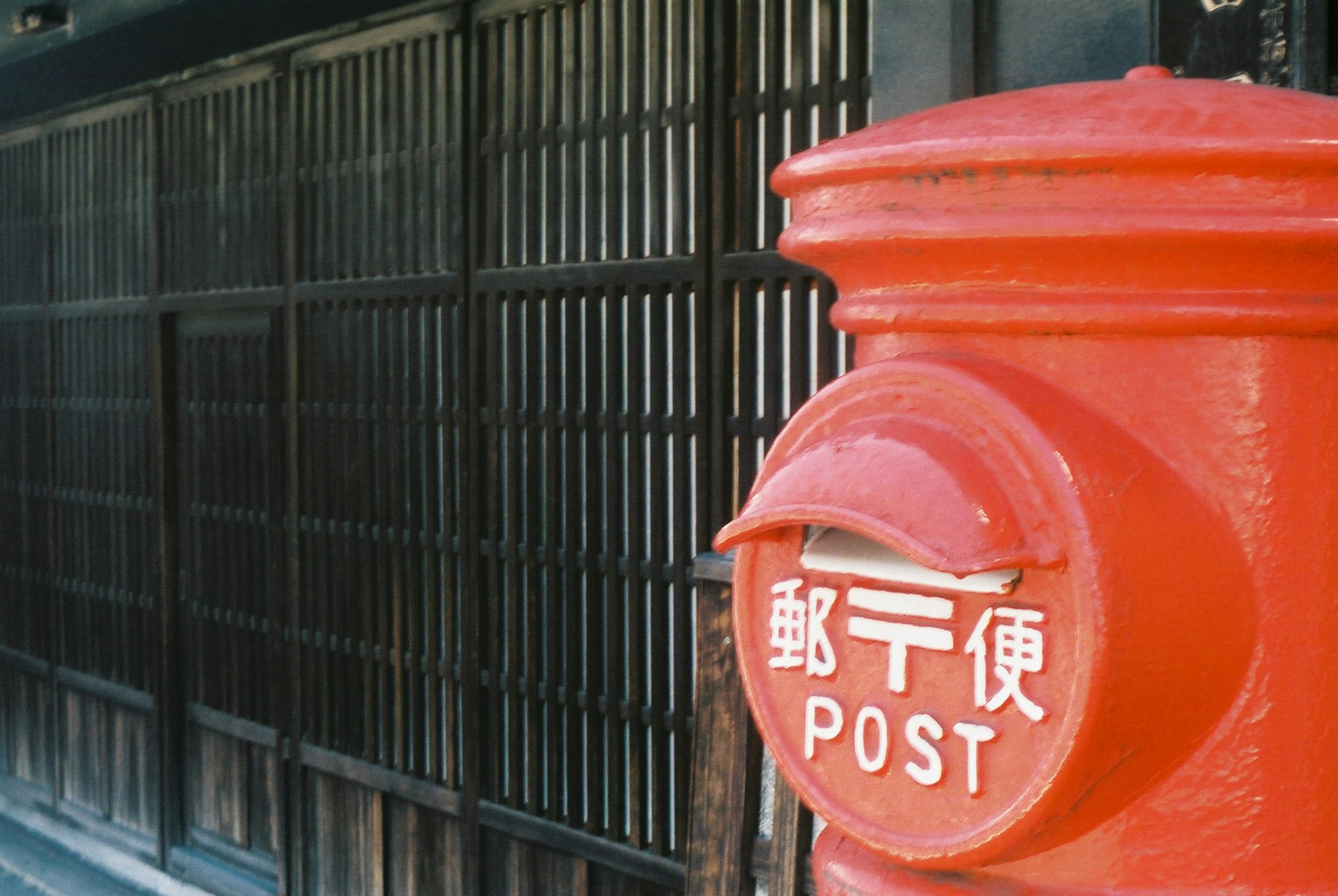 Red postal box with wooden slatted background