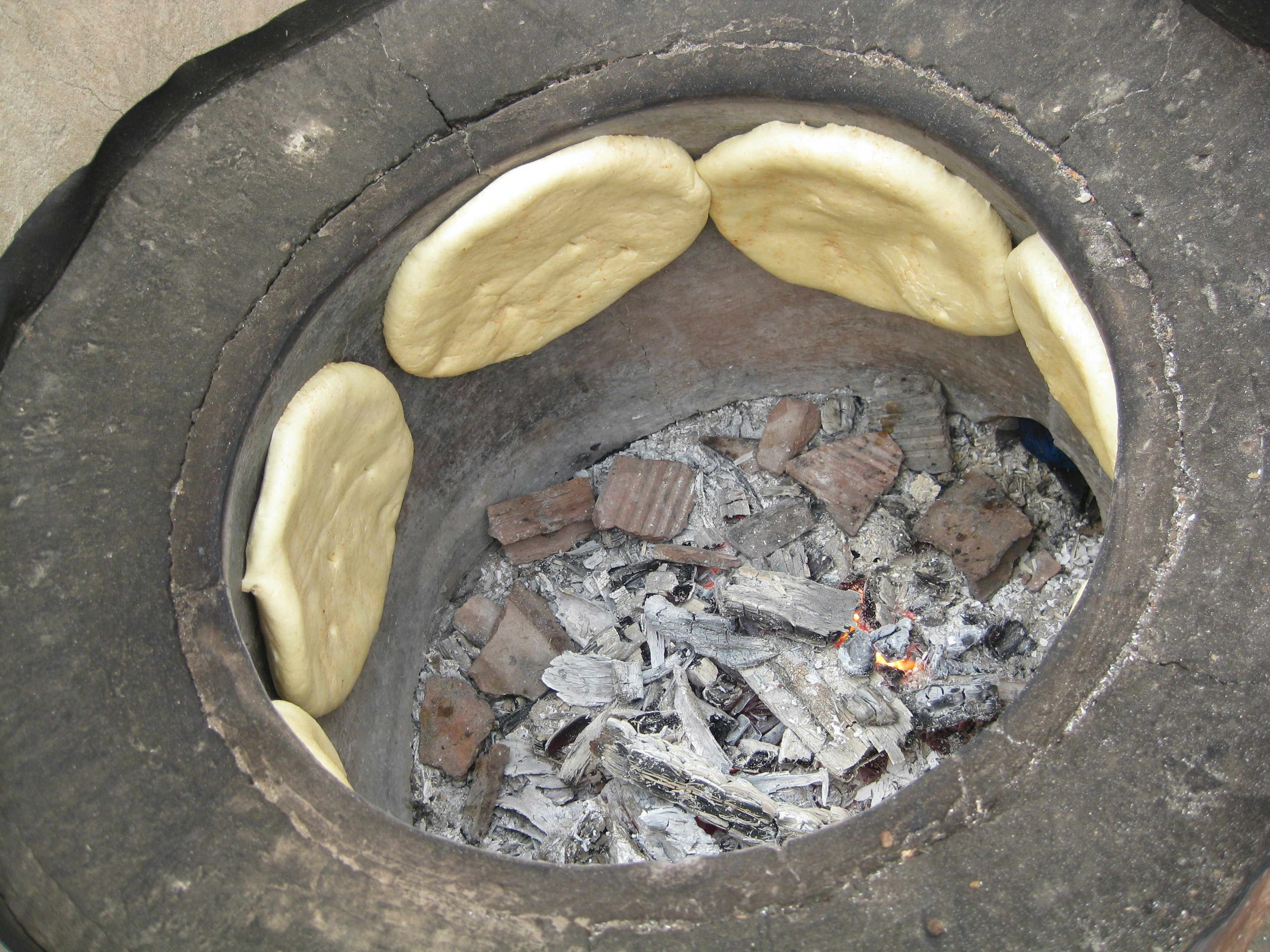 Dough being cooked in a traditional oven with ash