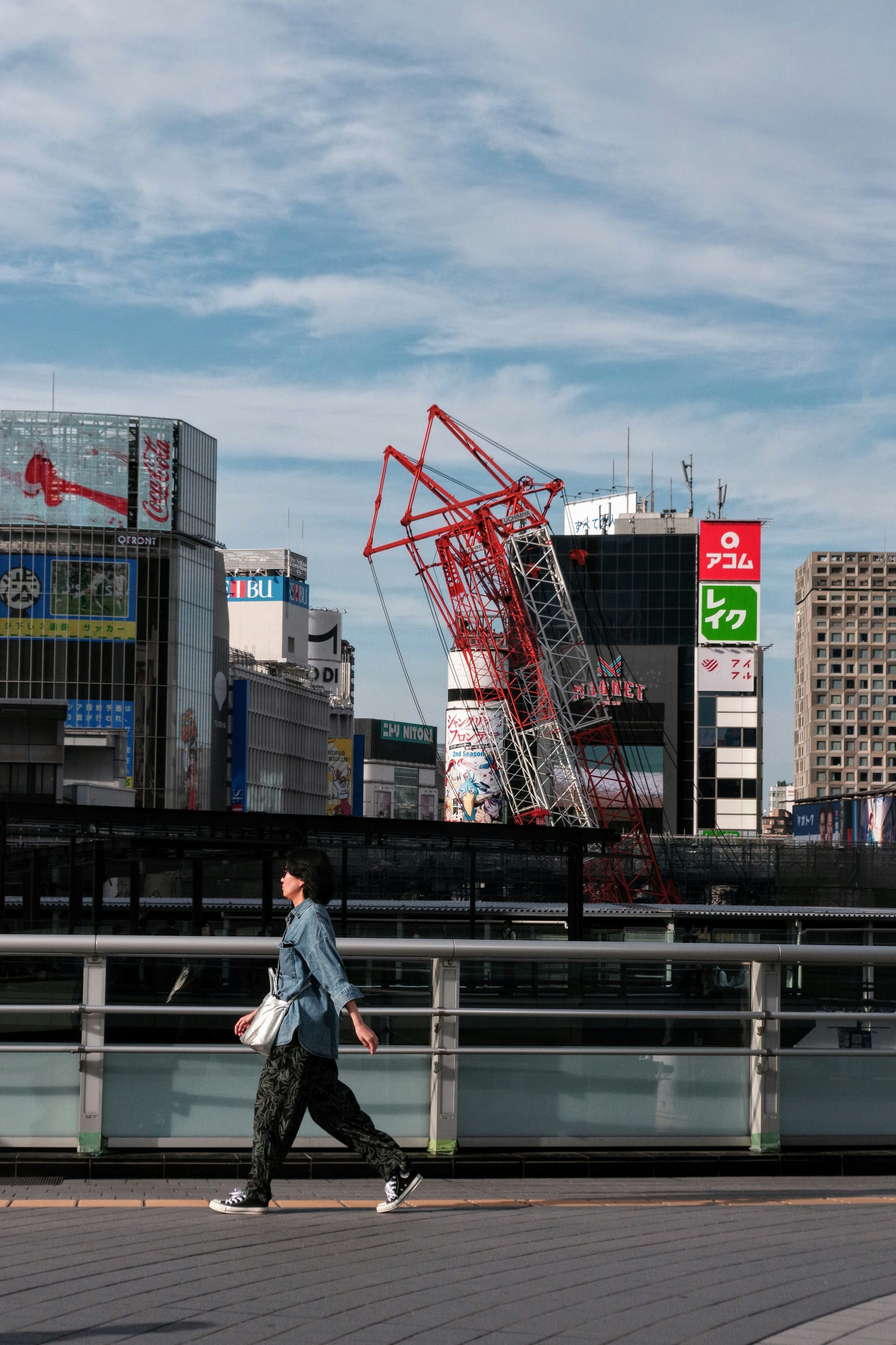 一个人在城市风景中行走，背景是建筑和起重机