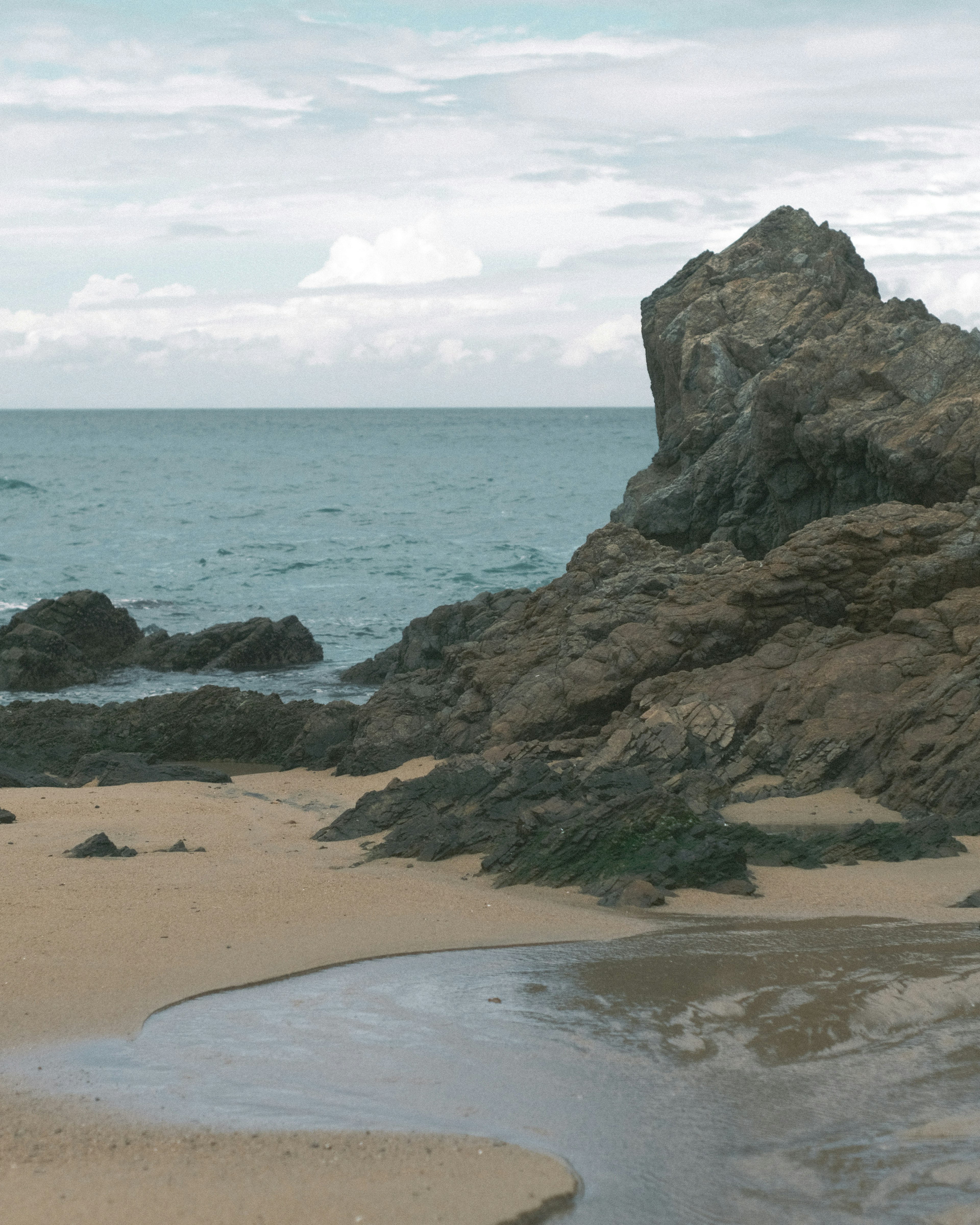 Pemandangan pantai dengan batu dan laut tenang