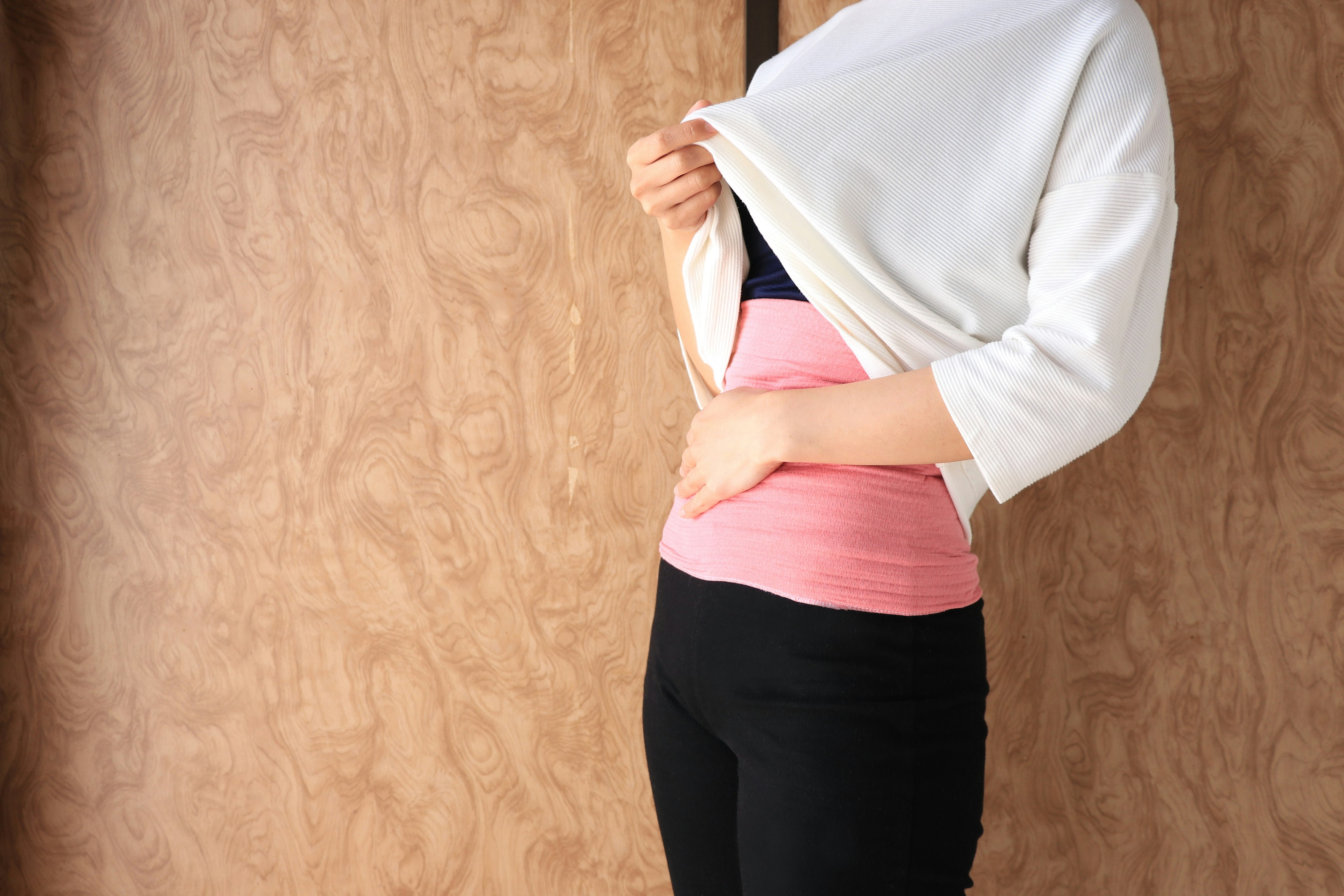 Une femme portant un bandeau abdominal rose en soulevant sa chemise