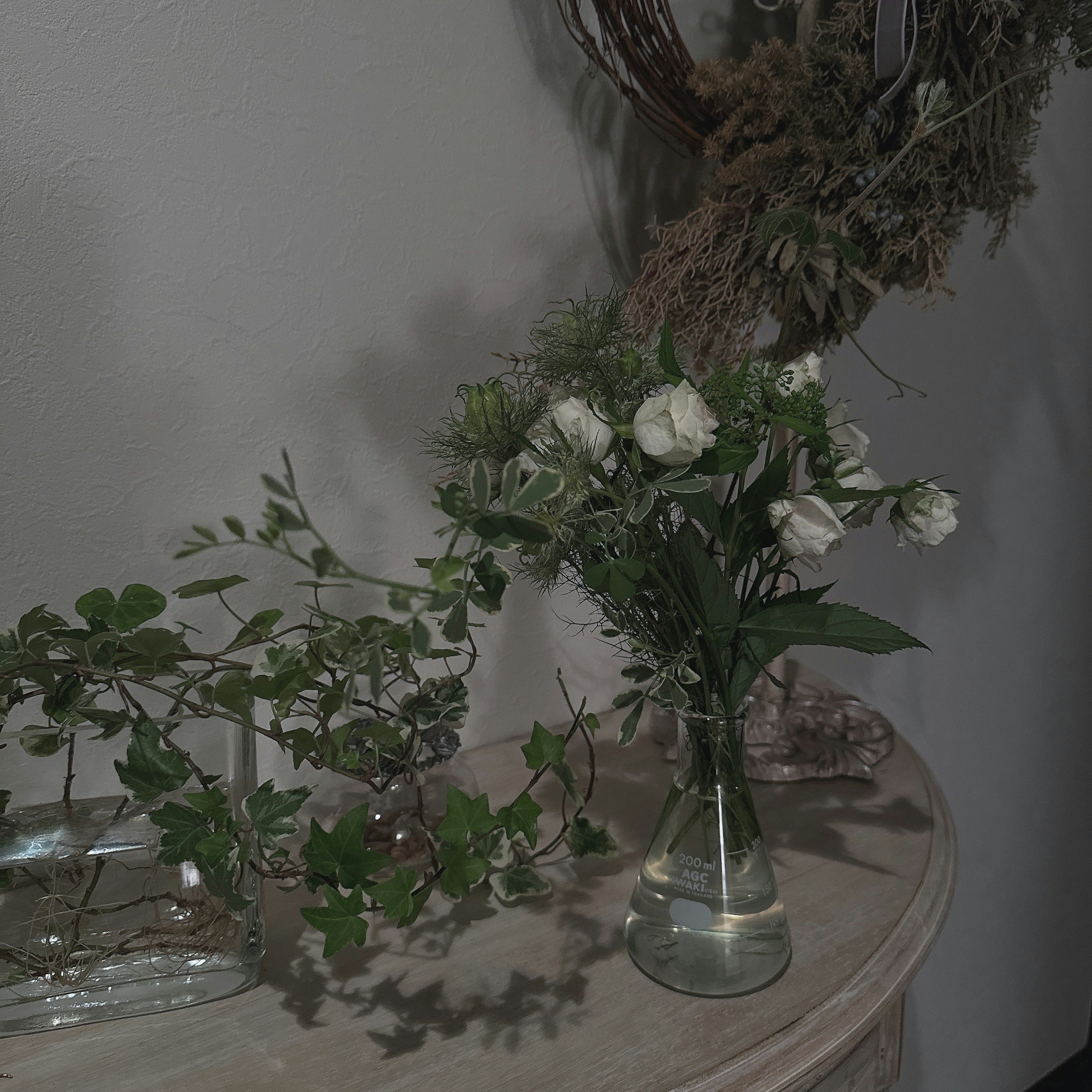 A vase with white roses and green foliage on a table