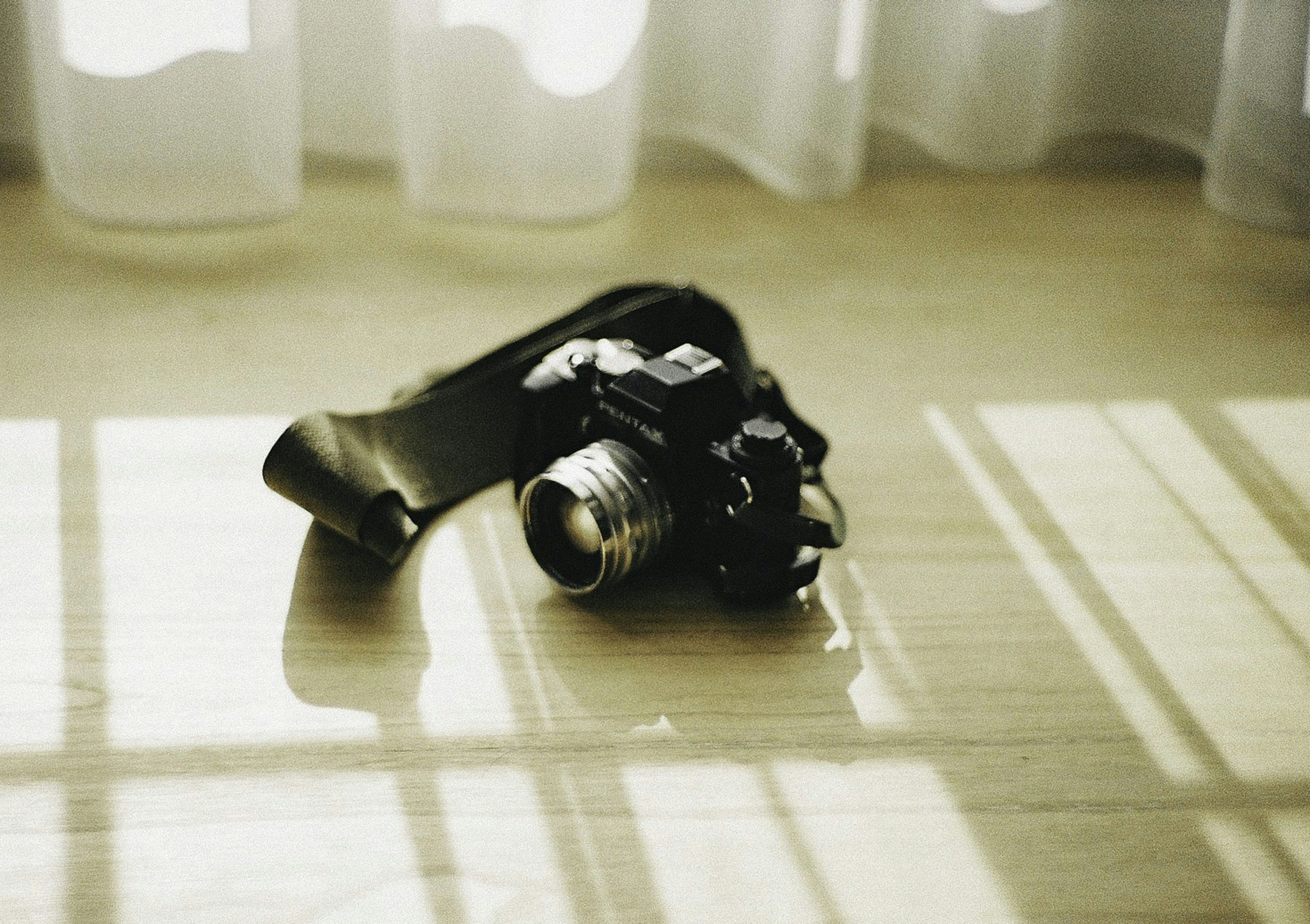 Camera resting on a wooden table with curtain shadows