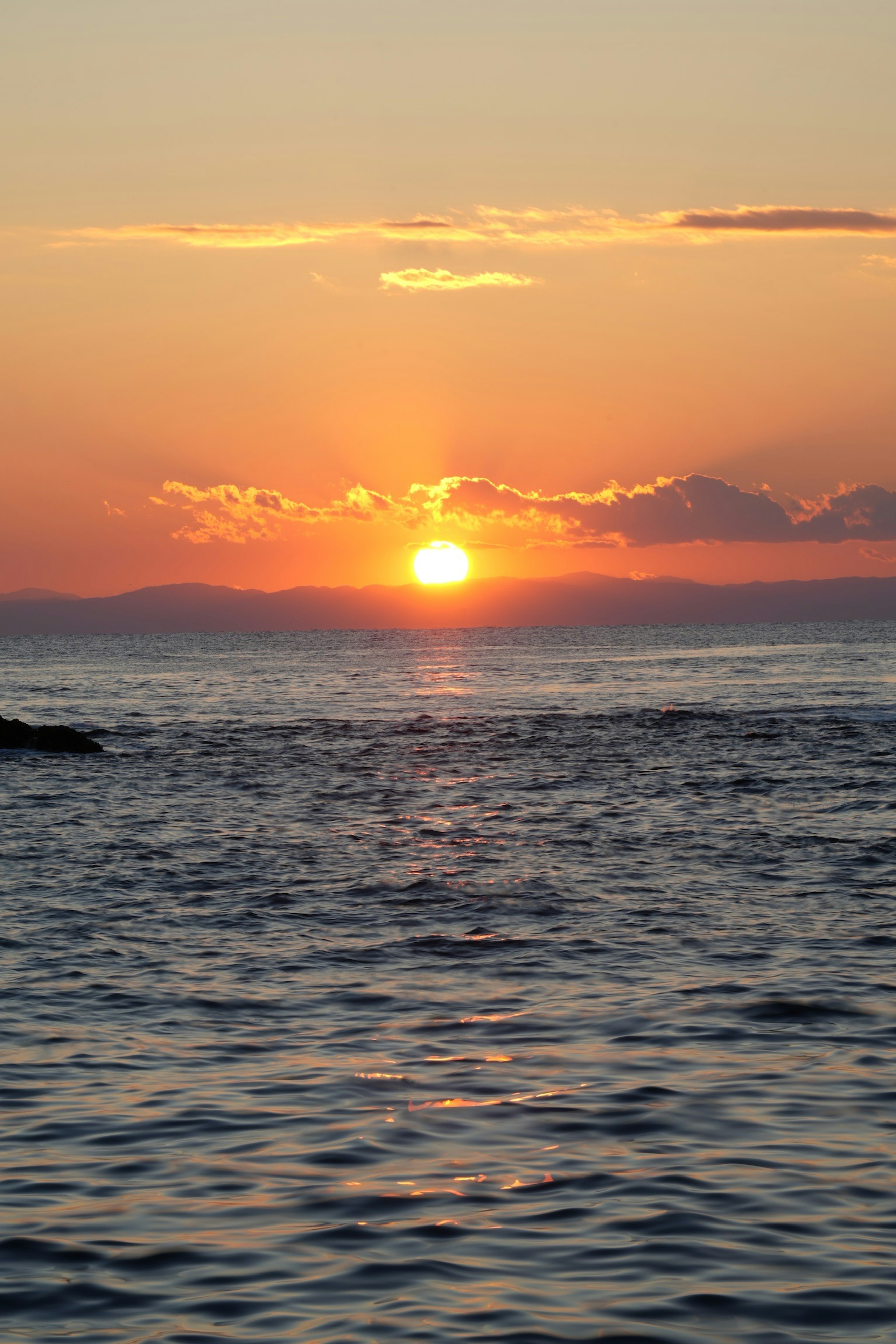 Coucher de soleil sur une mer calme avec des teintes orange et rose