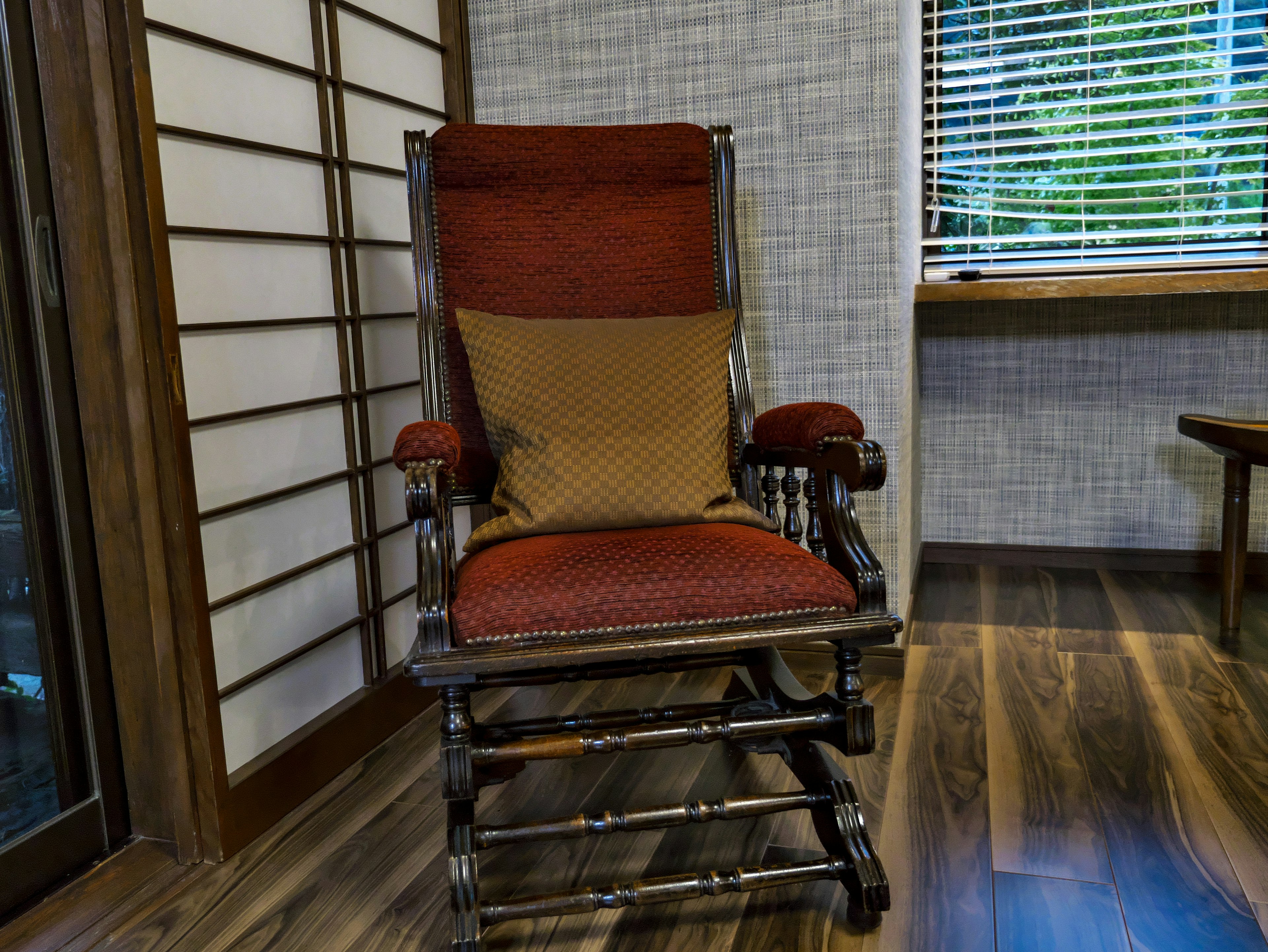 Une chaise berçante avec un coussin rouge placée dans une pièce de style japonais