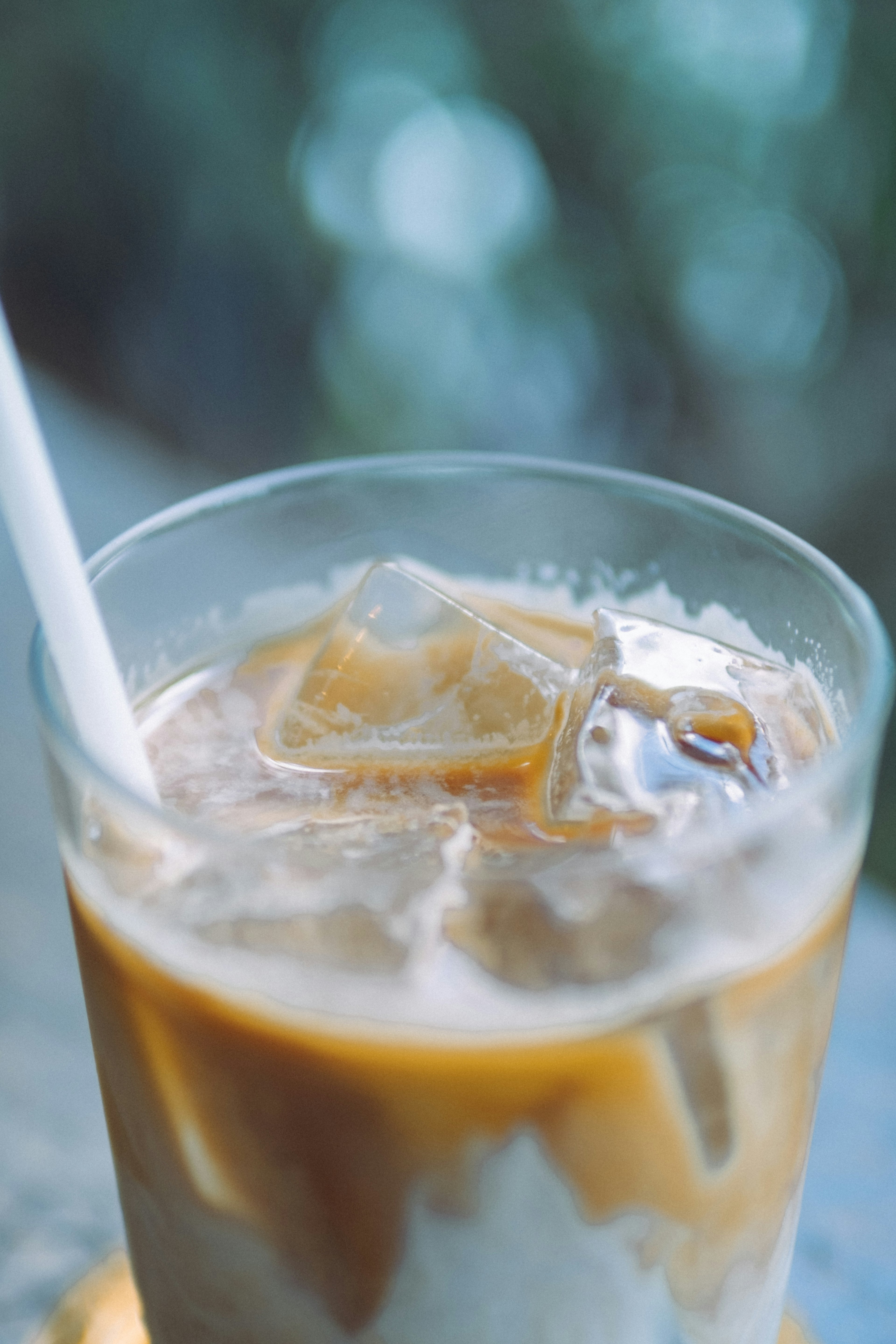 A glass of iced coffee with ice cubes and a straw