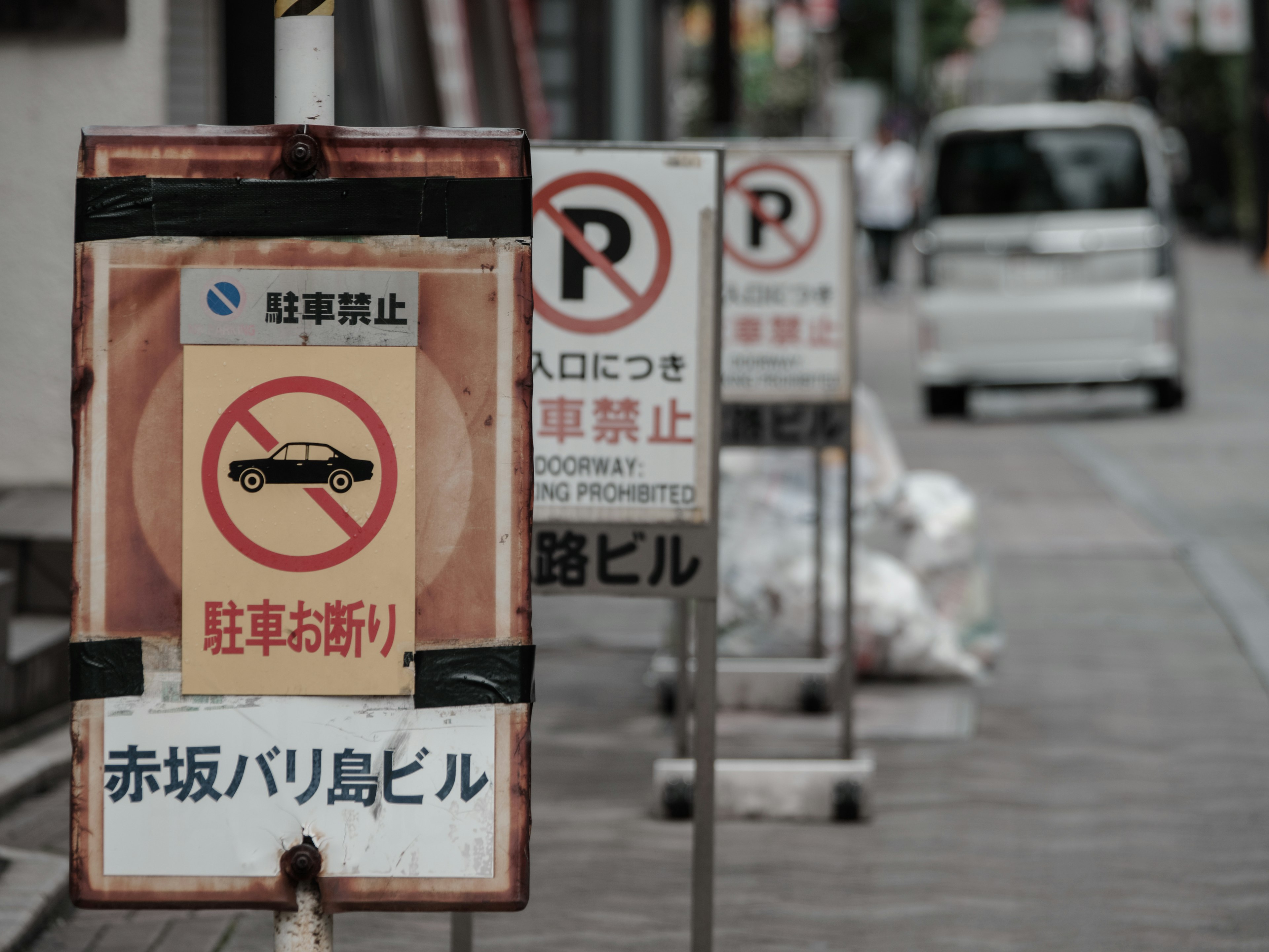 Escena de calle con señales de no estacionar y letrero del edificio Akasaka Bali Island