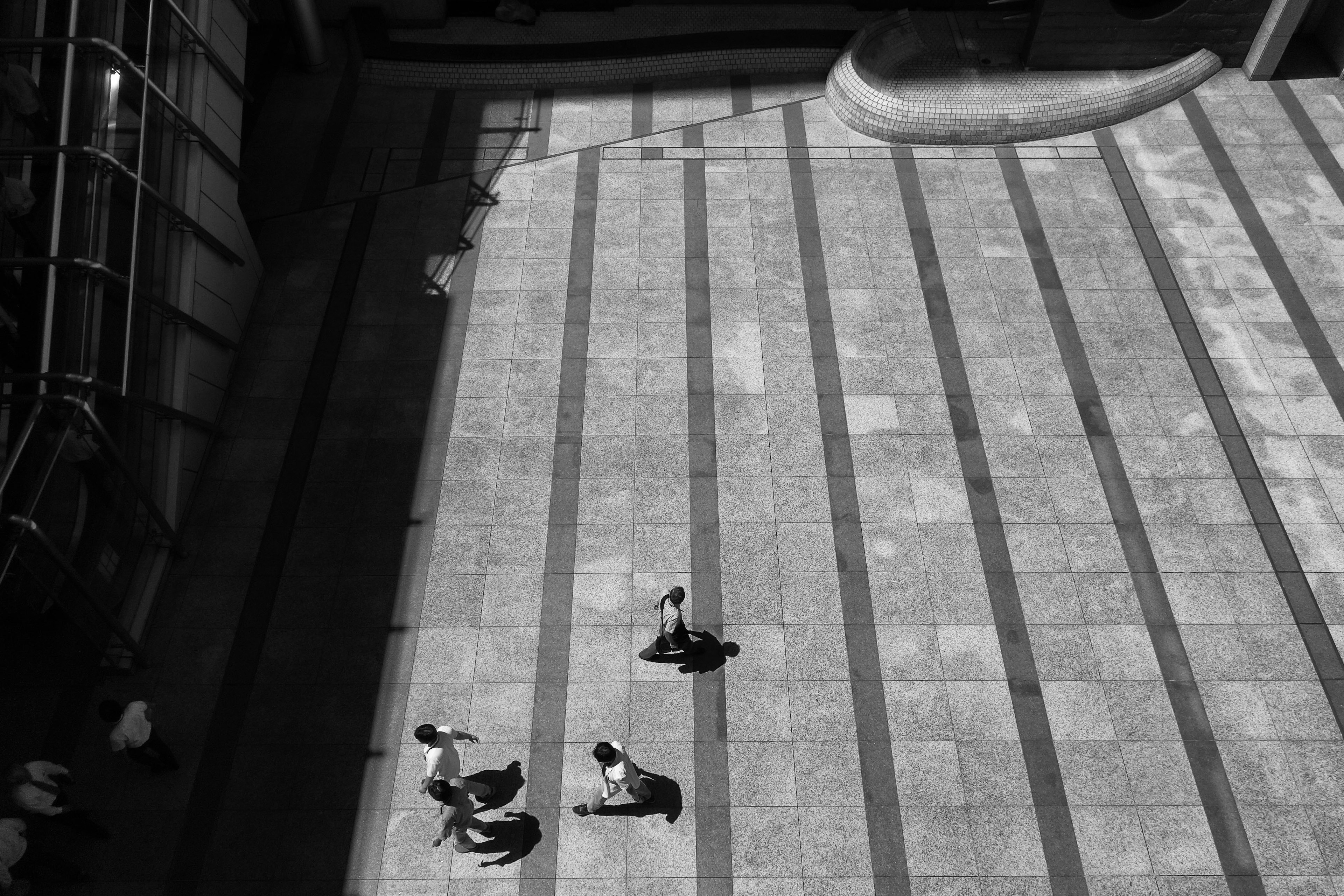 Aerial view of people walking in a monochrome urban plaza