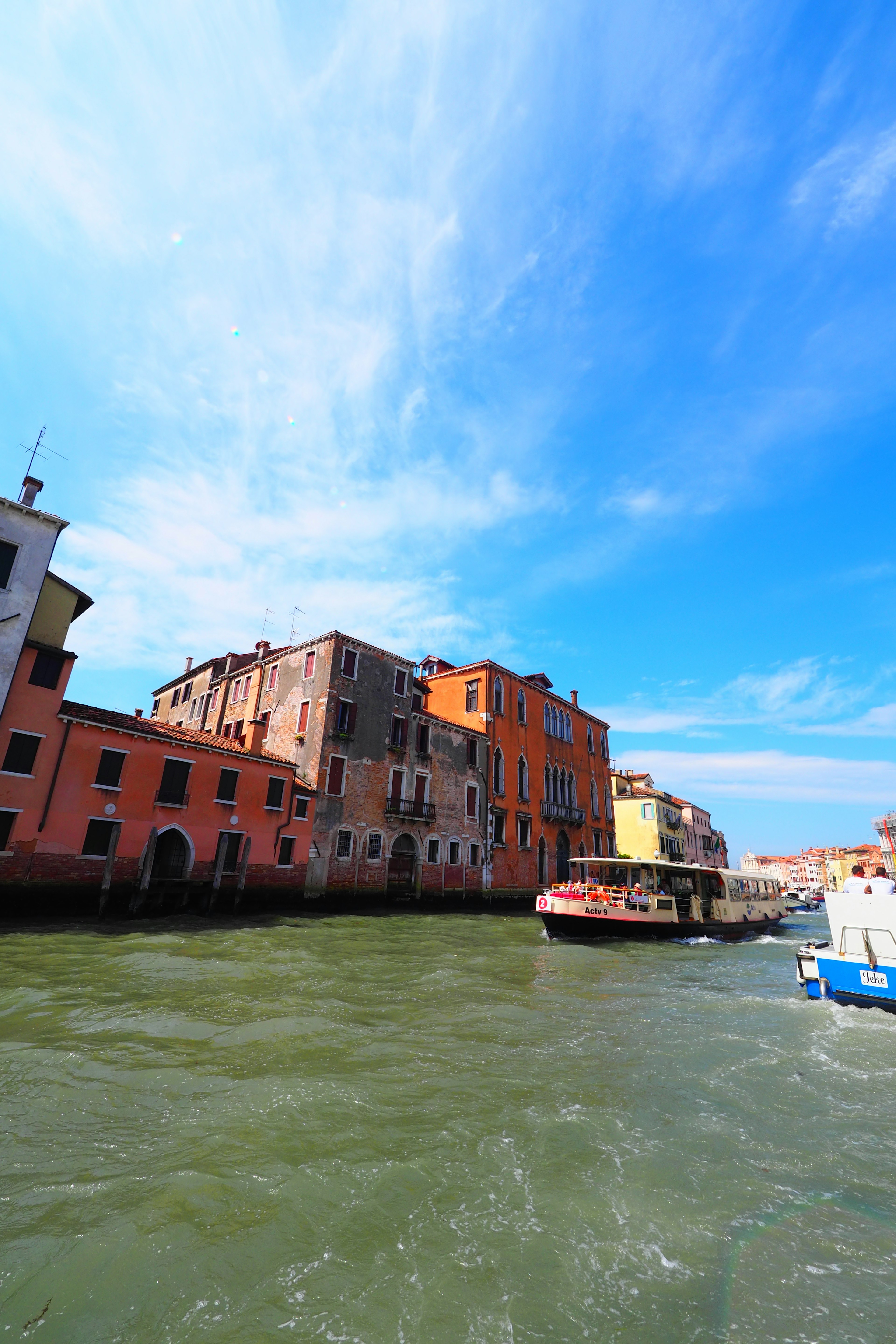 Colorful buildings lining a canal under a blue sky with rippling water