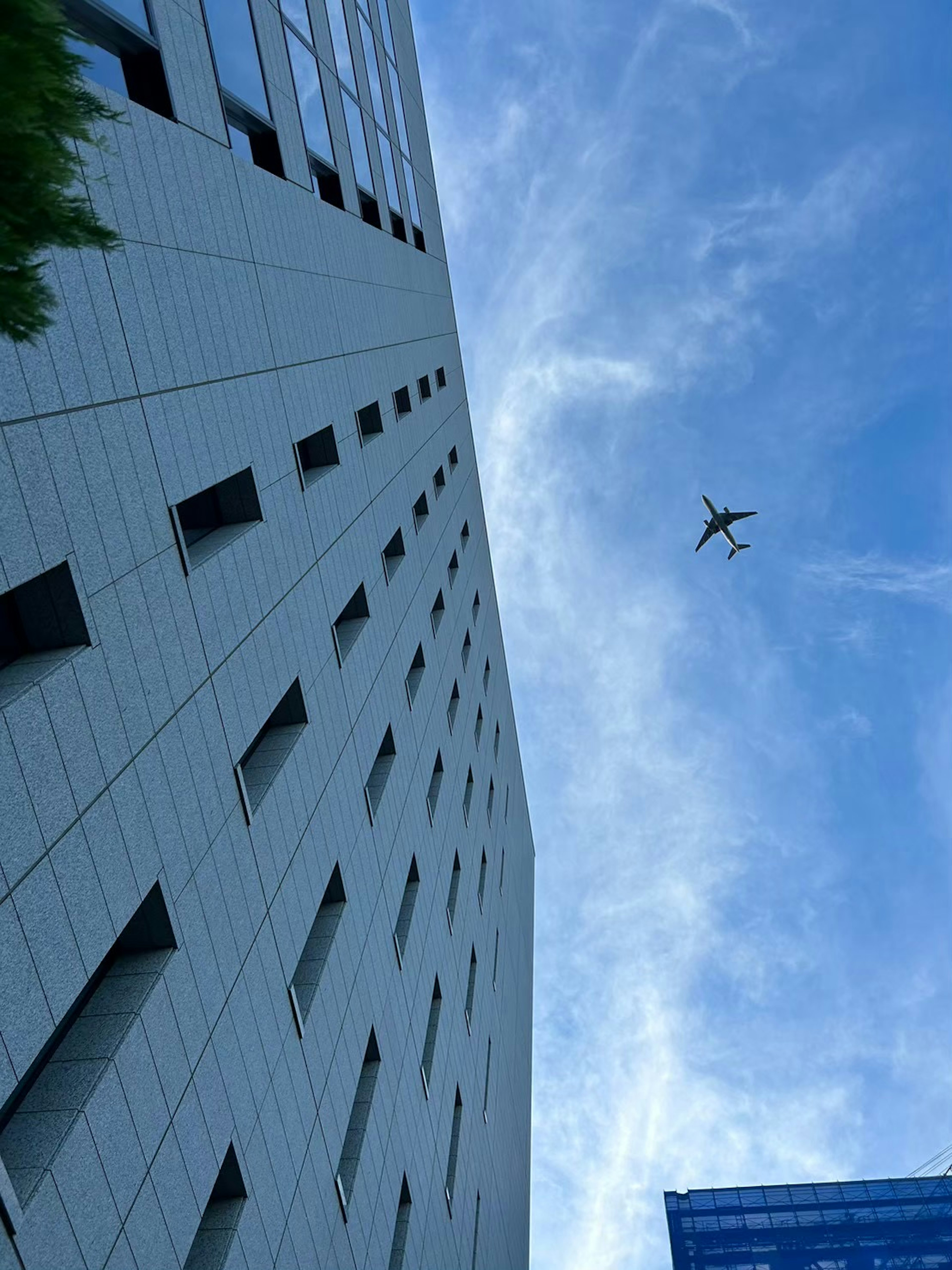 高層ビルの下から見上げた空に飛ぶドローン