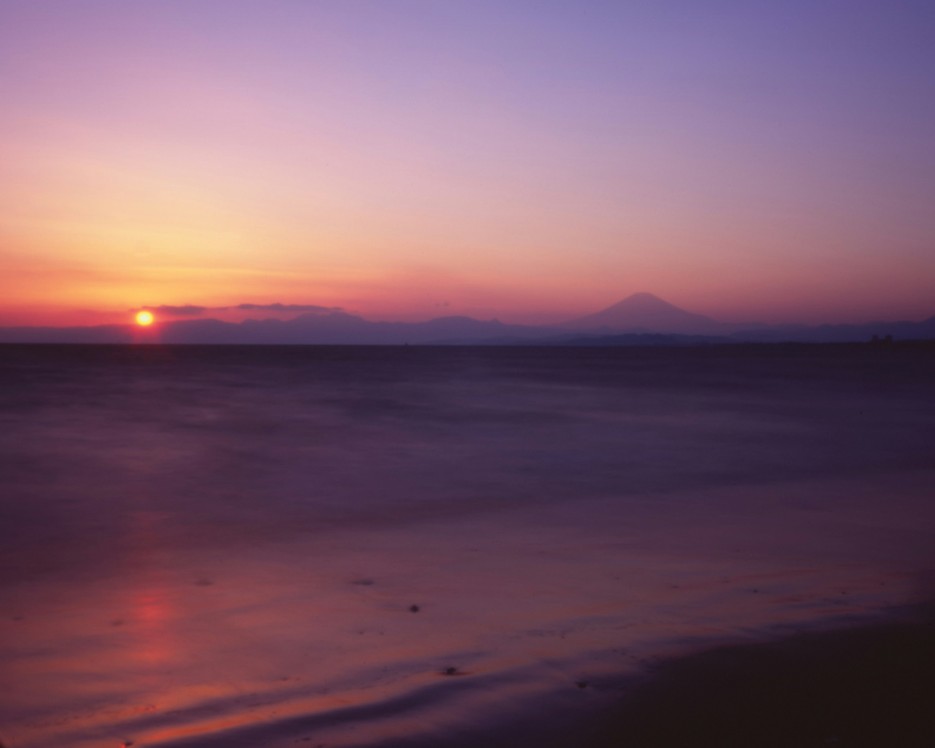 Hermoso paisaje de un atardecer sobre el mar con silueta de montaña