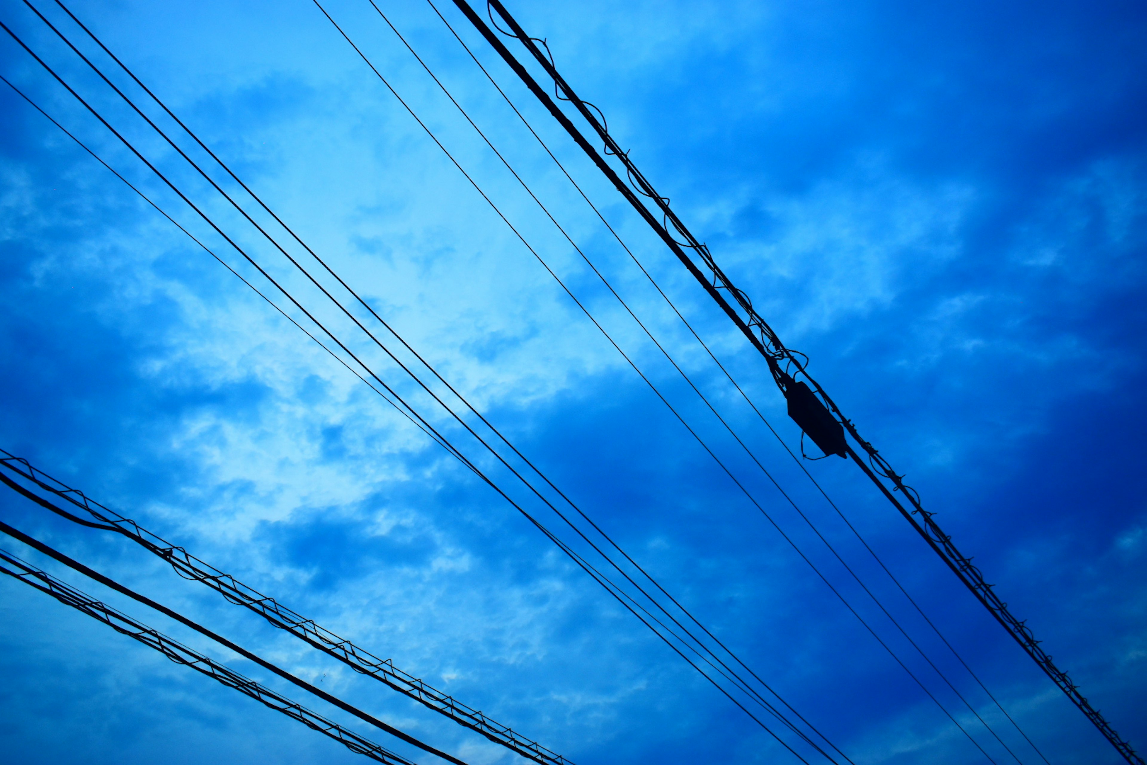 Power lines against a blue sky with clouds