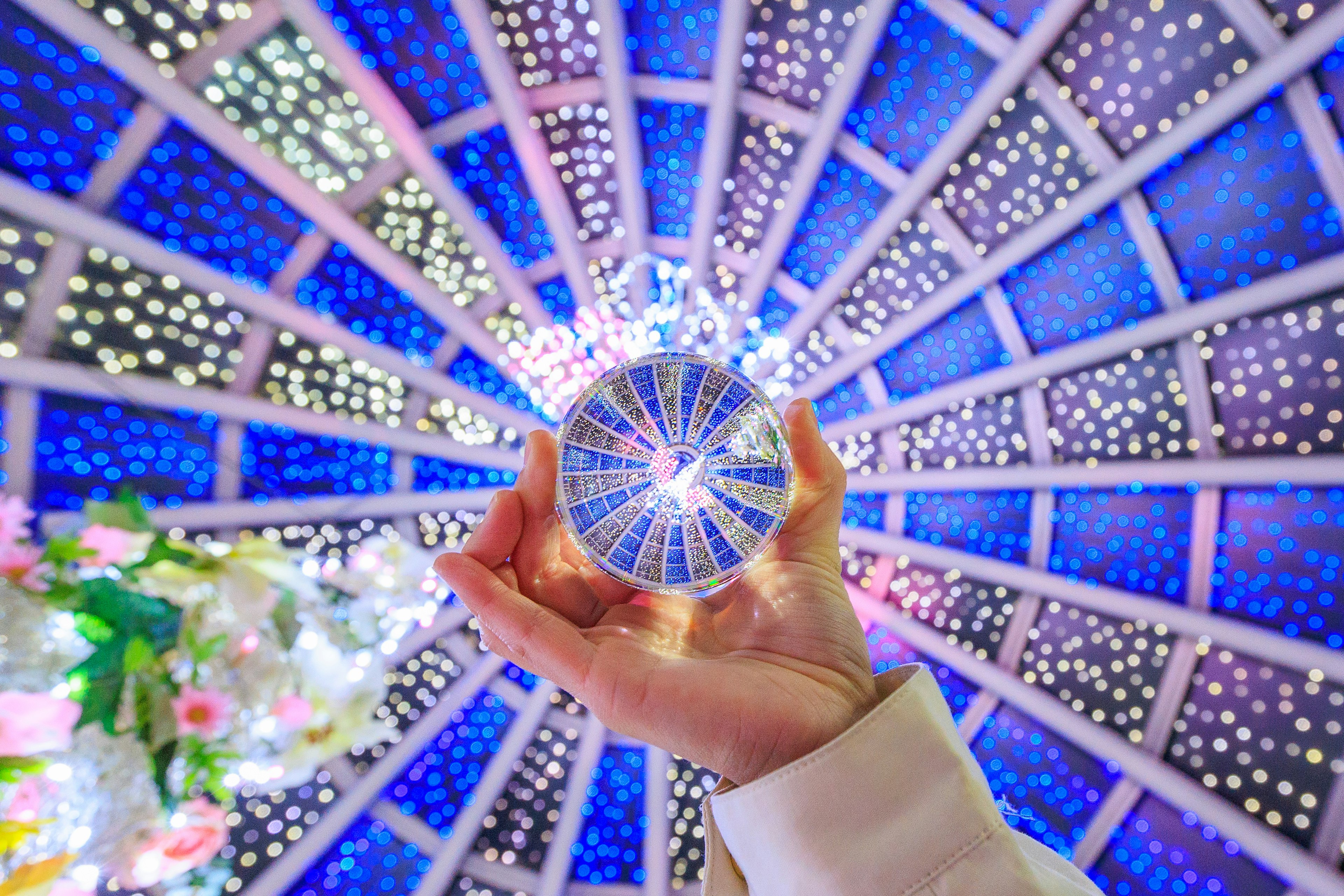 Une main tenant une boule en cristal avec un beau motif lumineux bleu au plafond