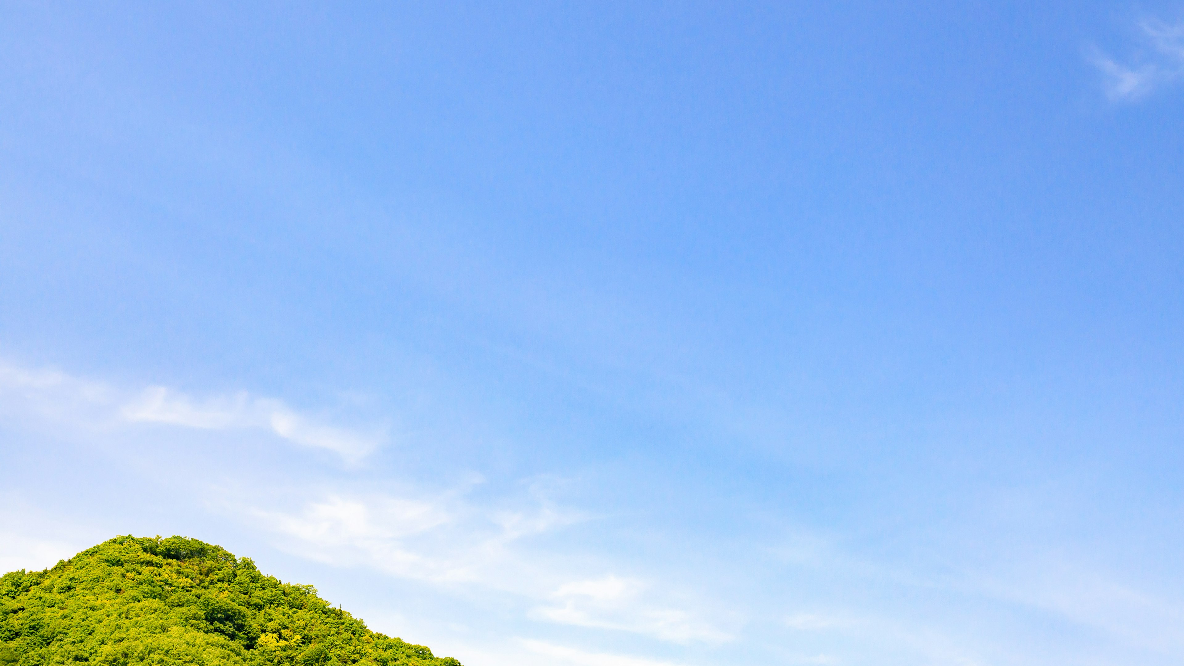 Paisaje con cielo azul y colina verde