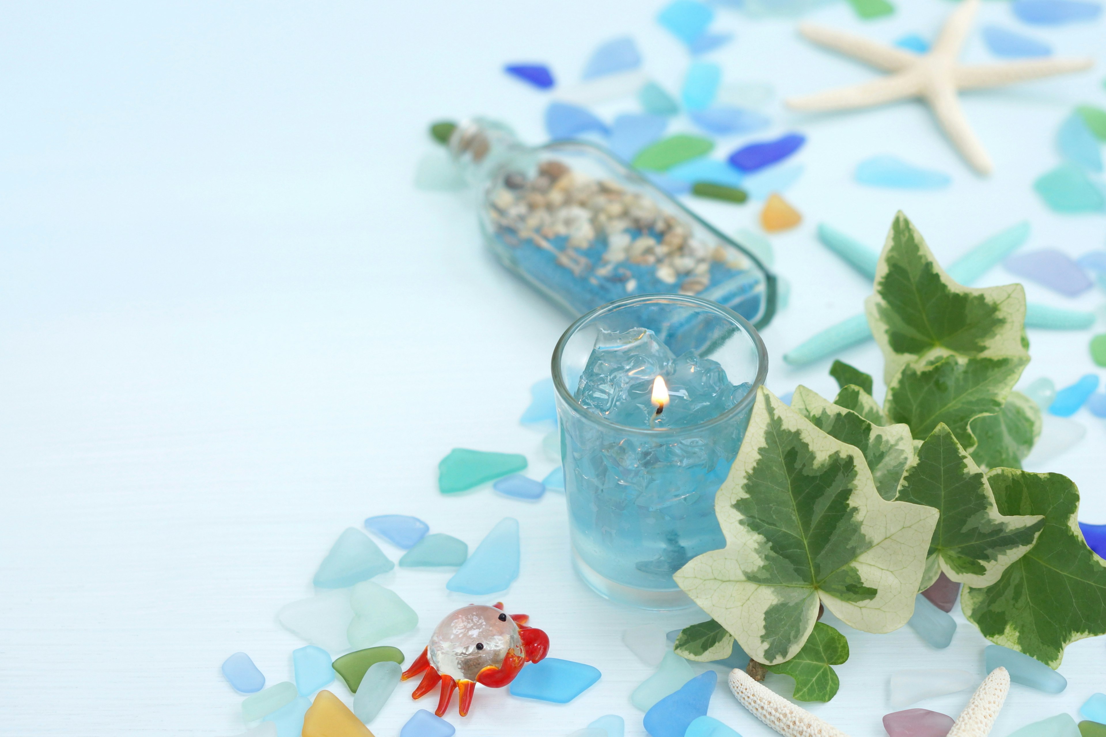 Candela blu con una bottiglia di conchiglie in una decorazione a tema costiero