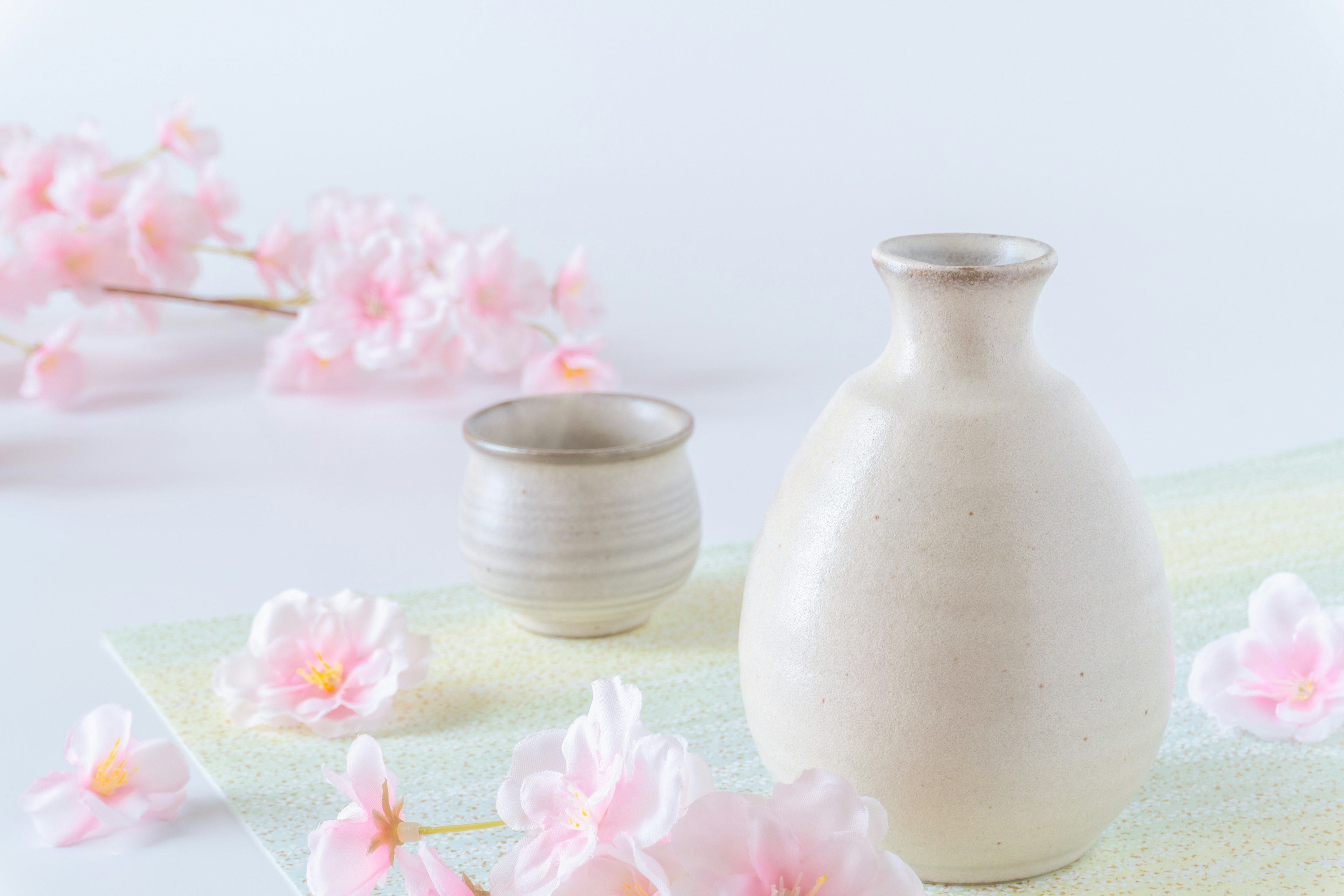 Still life featuring cherry blossoms with a ceramic vase and cup