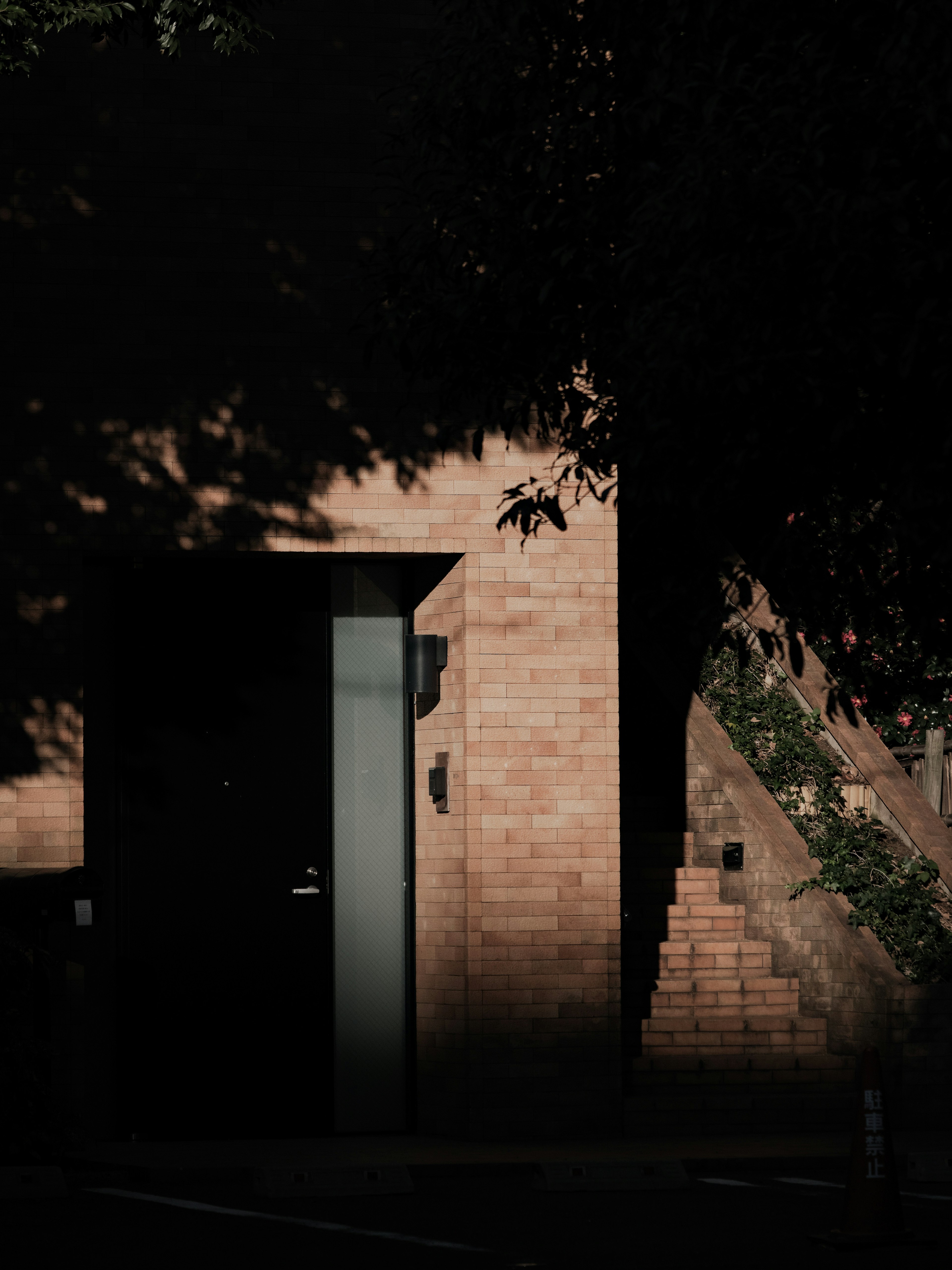 Building with brick wall and glass door in shadow