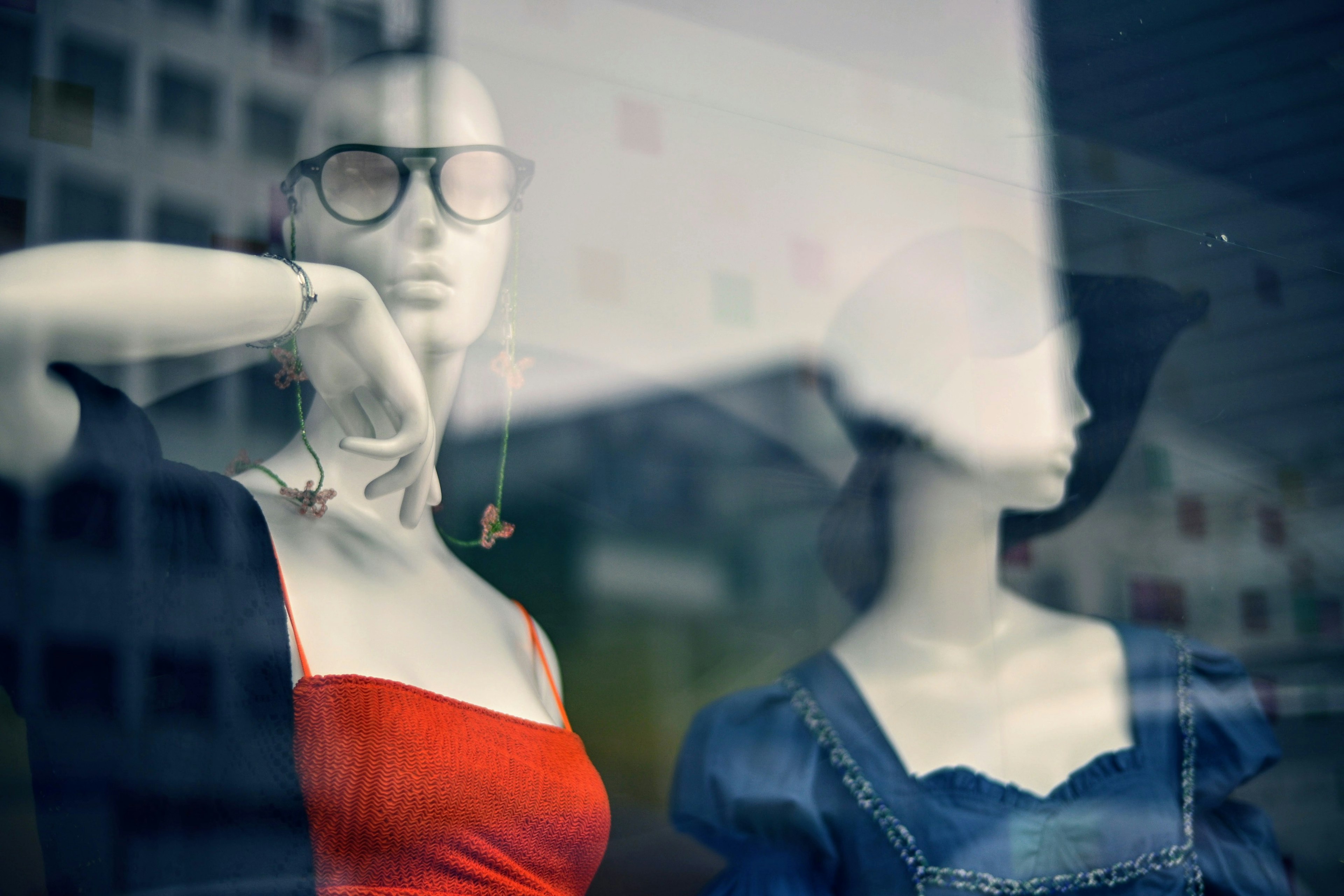 Mannequins in red dress and blue denim displayed in a shop window