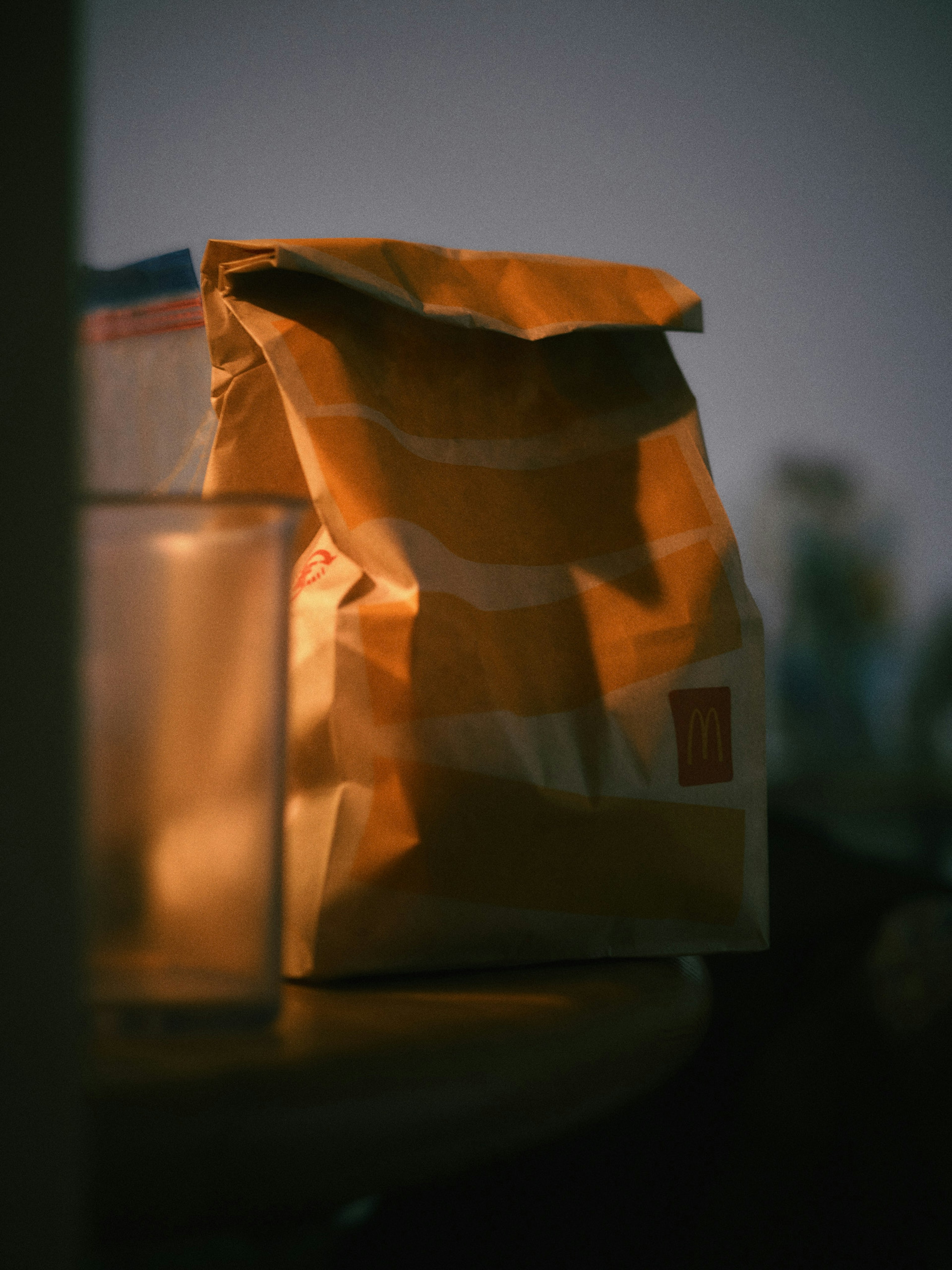 Image of a brown paper bag on a table with a transparent glass