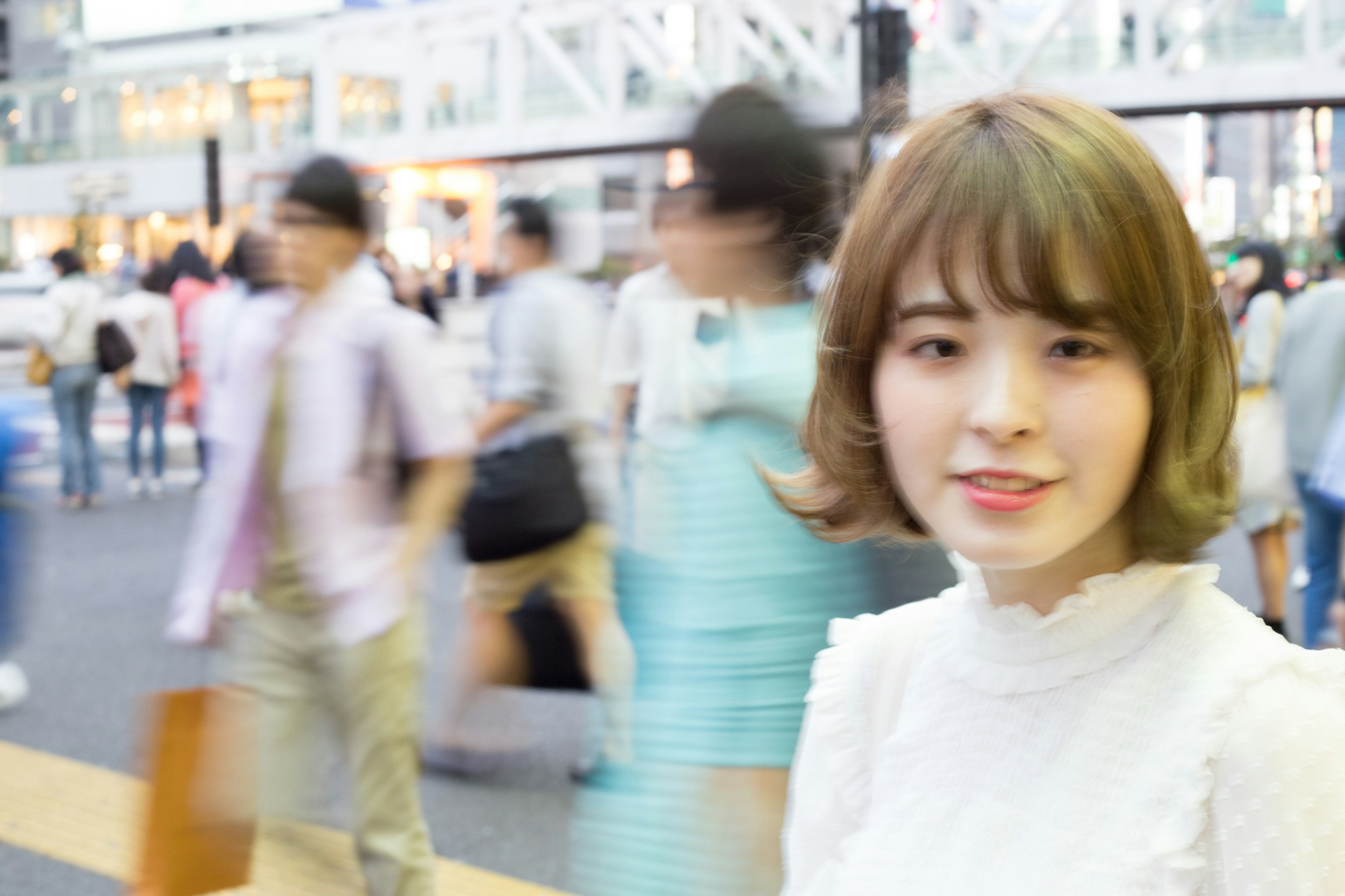 Portrait of a smiling woman in a bustling city street with blurred pedestrians