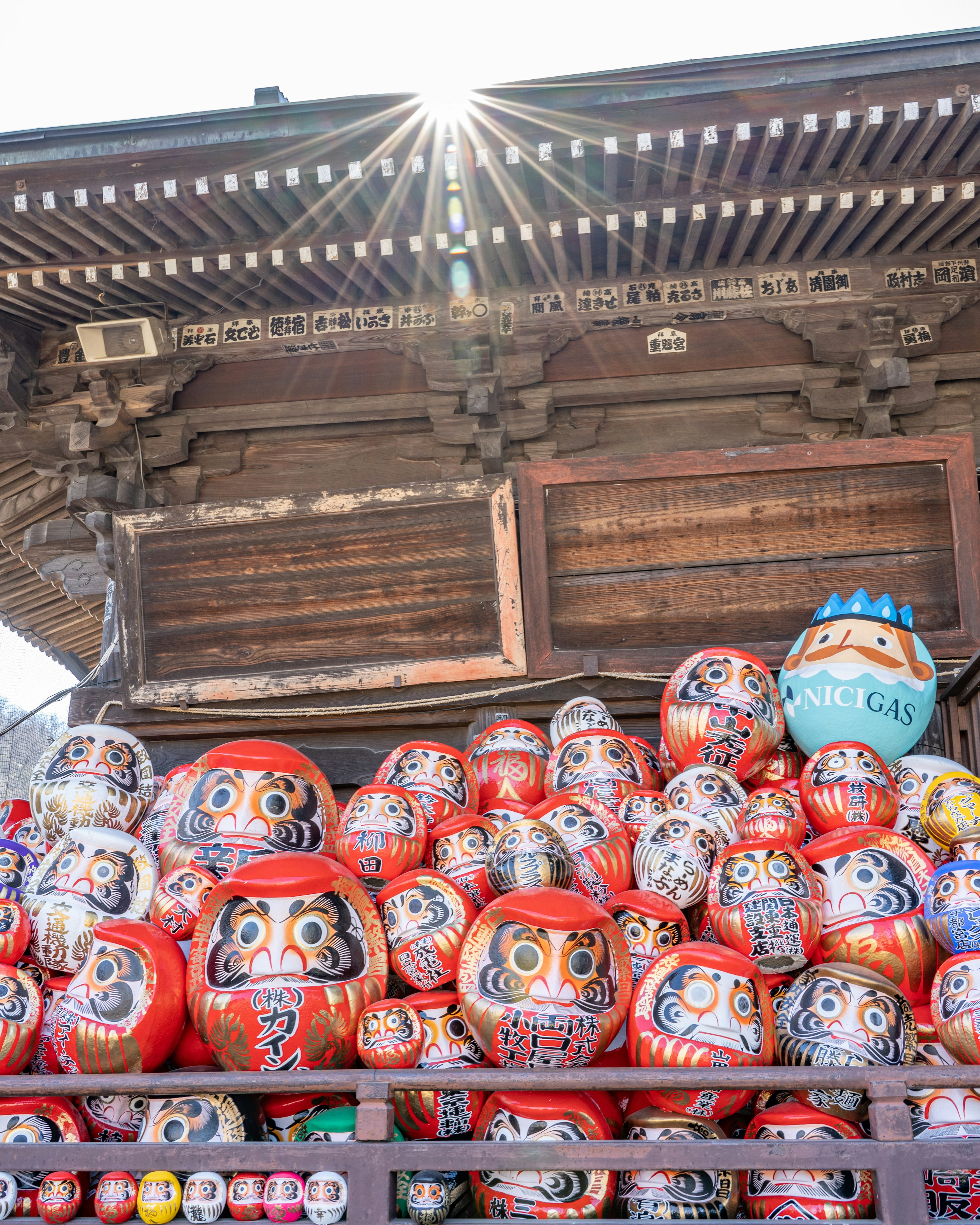 Doll daruma colorate impilate davanti a un edificio tradizionale con luce solare