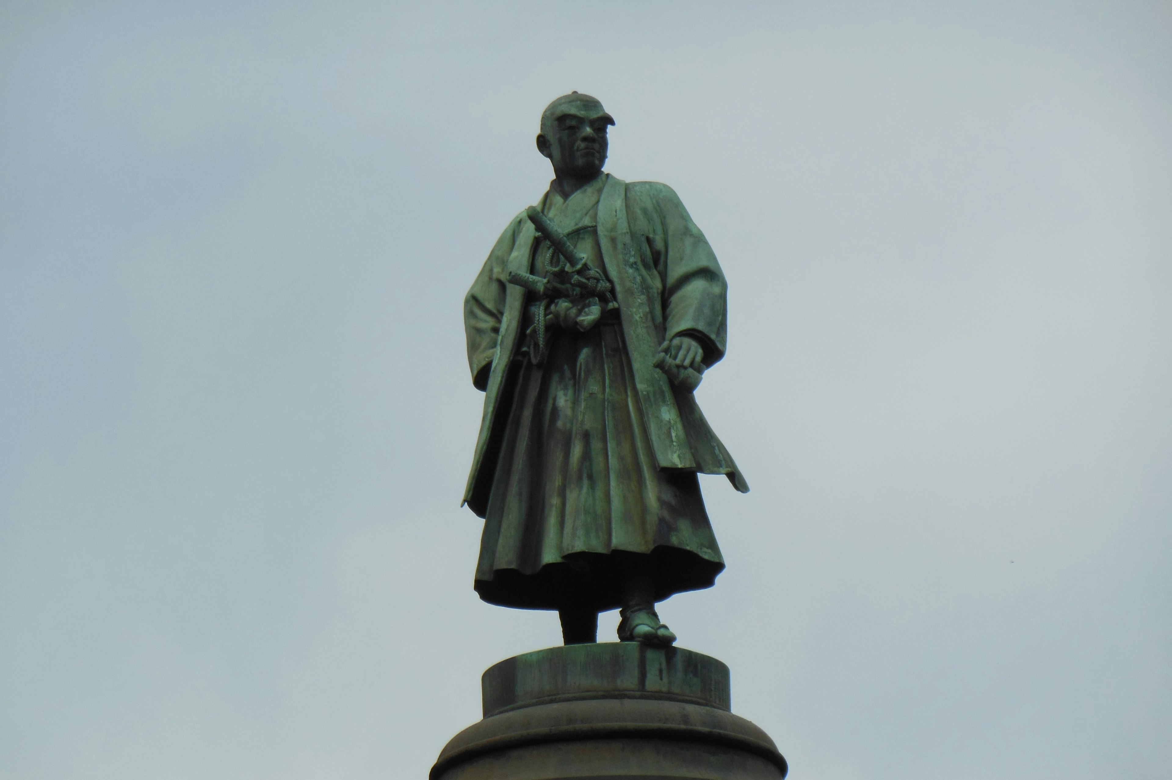 Statue d'un homme en tenue traditionnelle se tenant sur un piédestal