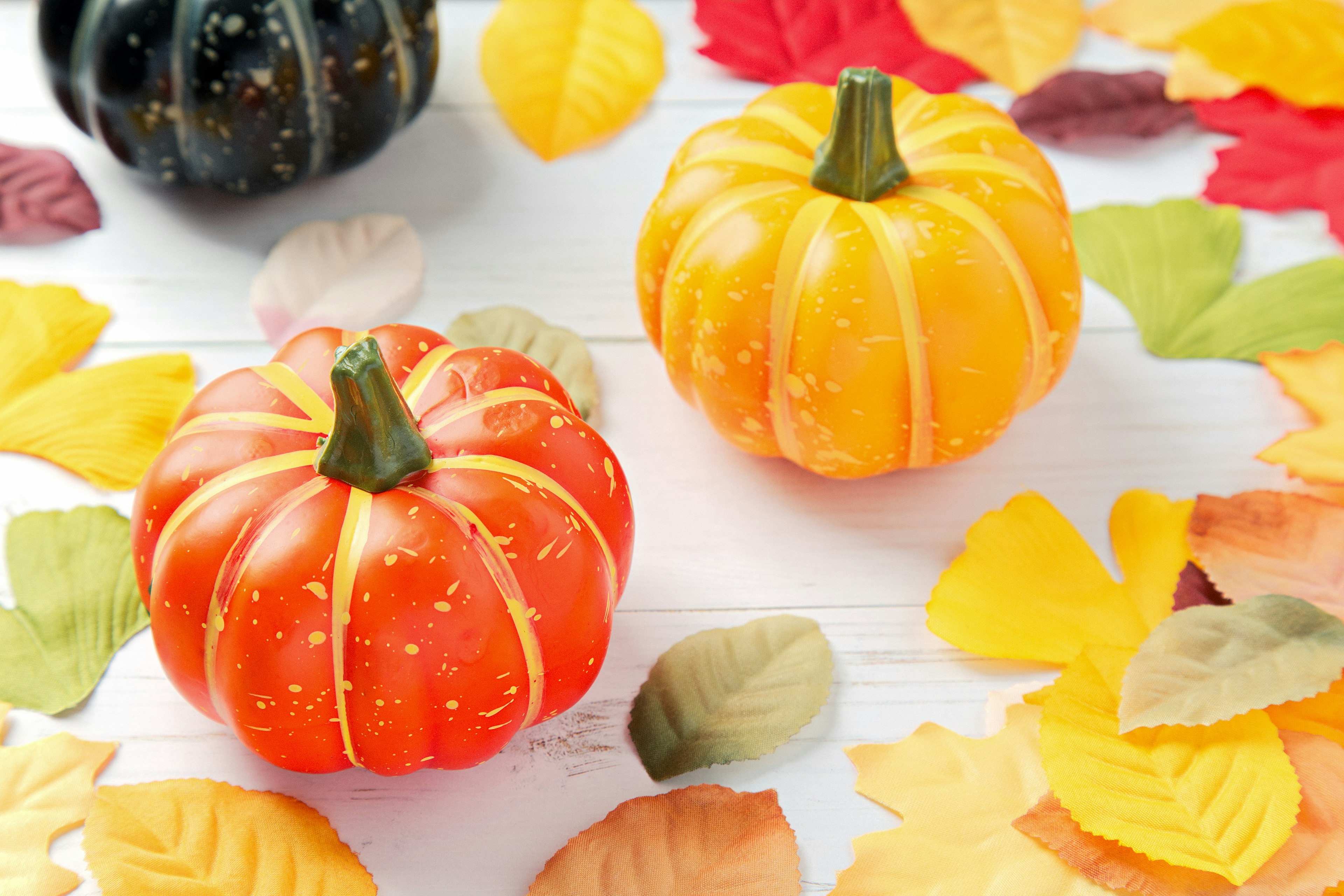 Colorful mini pumpkins surrounded by autumn leaves