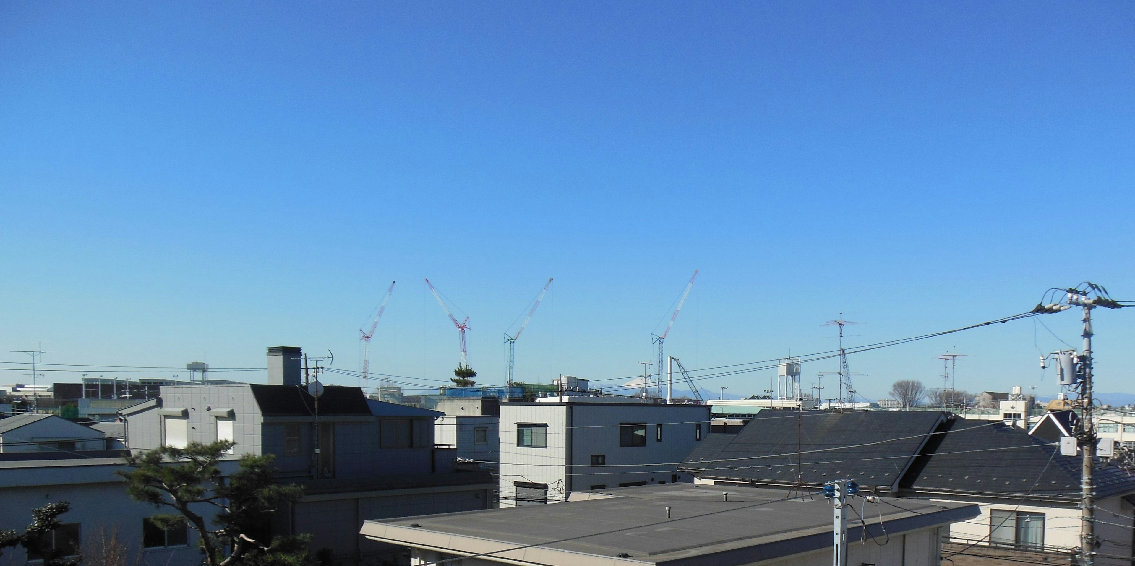 Residential area under a clear blue sky with illuminated rooftops and utility poles