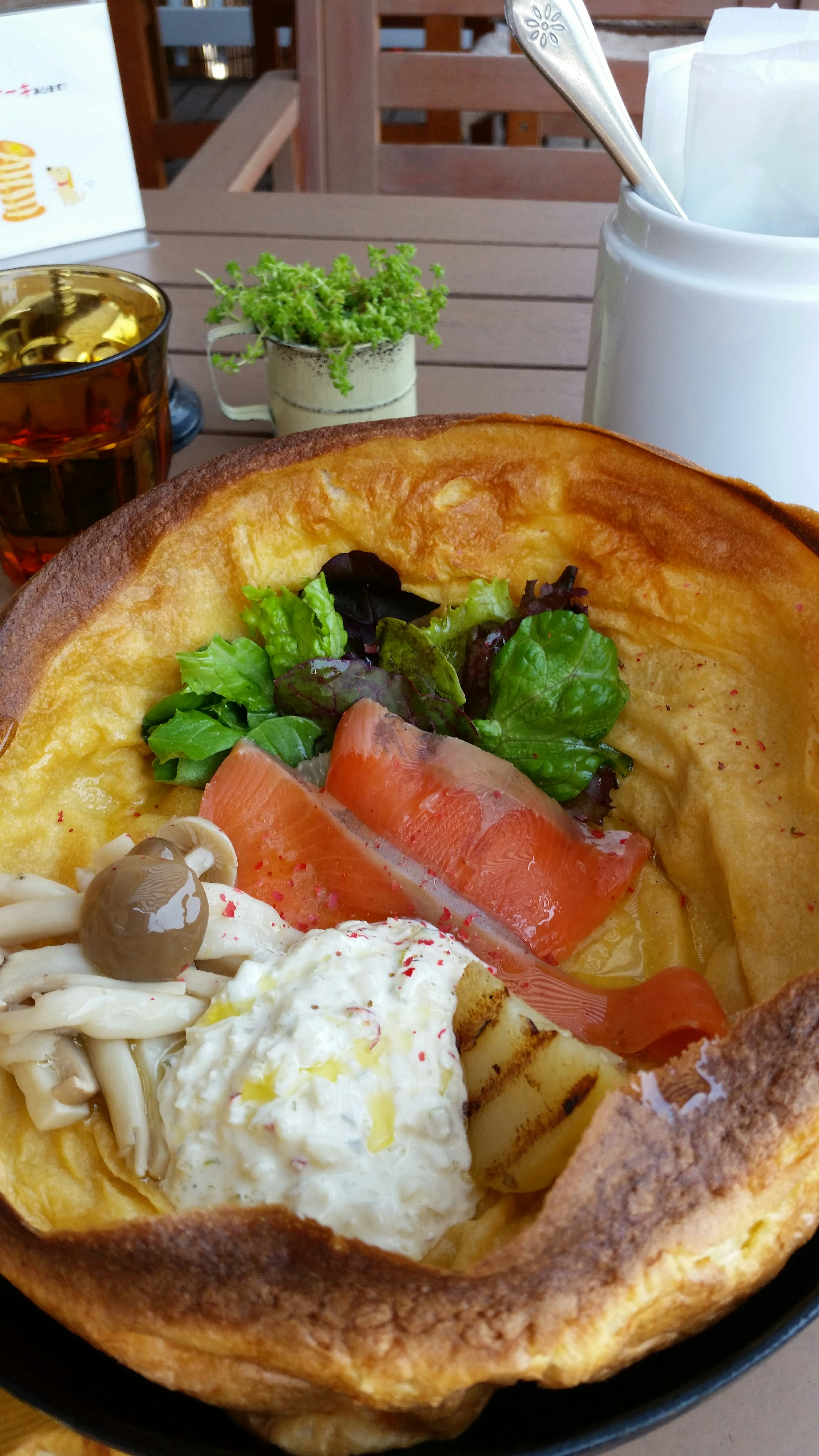 A large bread bowl filled with salad, smoked salmon, egg, and mushrooms