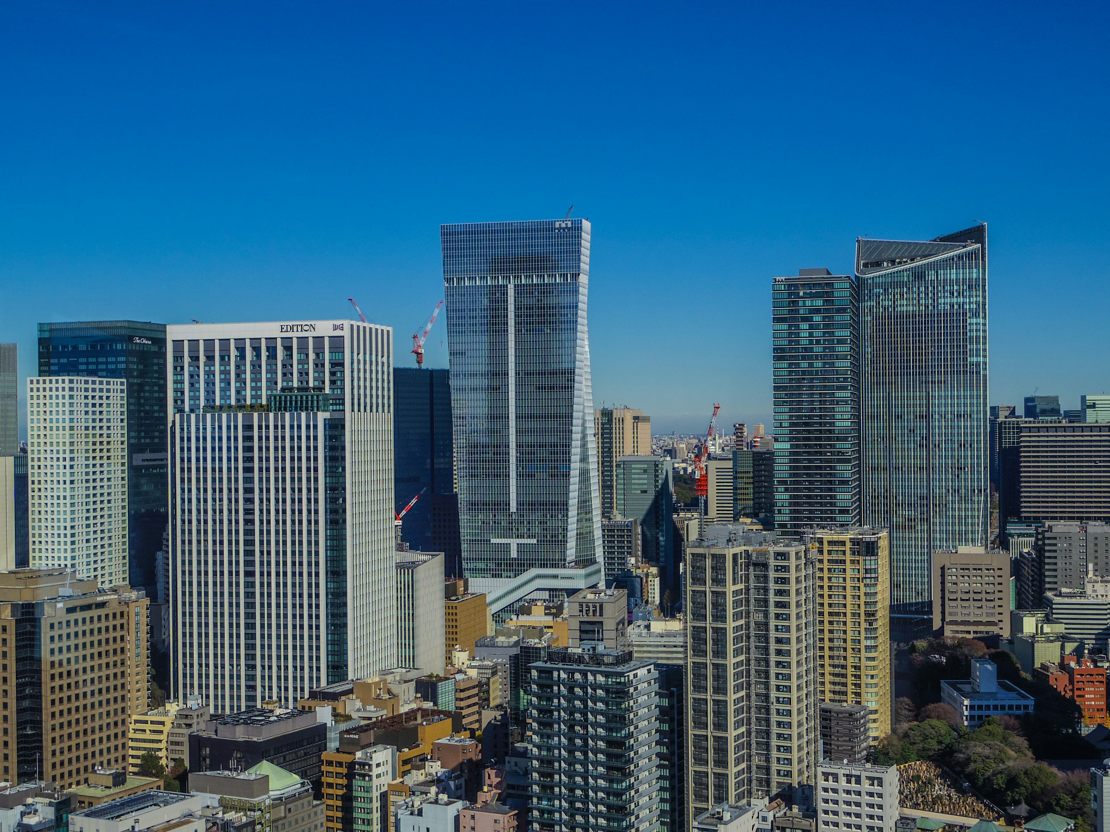 Luftaufnahme einer Stadtlandschaft mit modernen Wolkenkratzern unter einem hellblauen Himmel