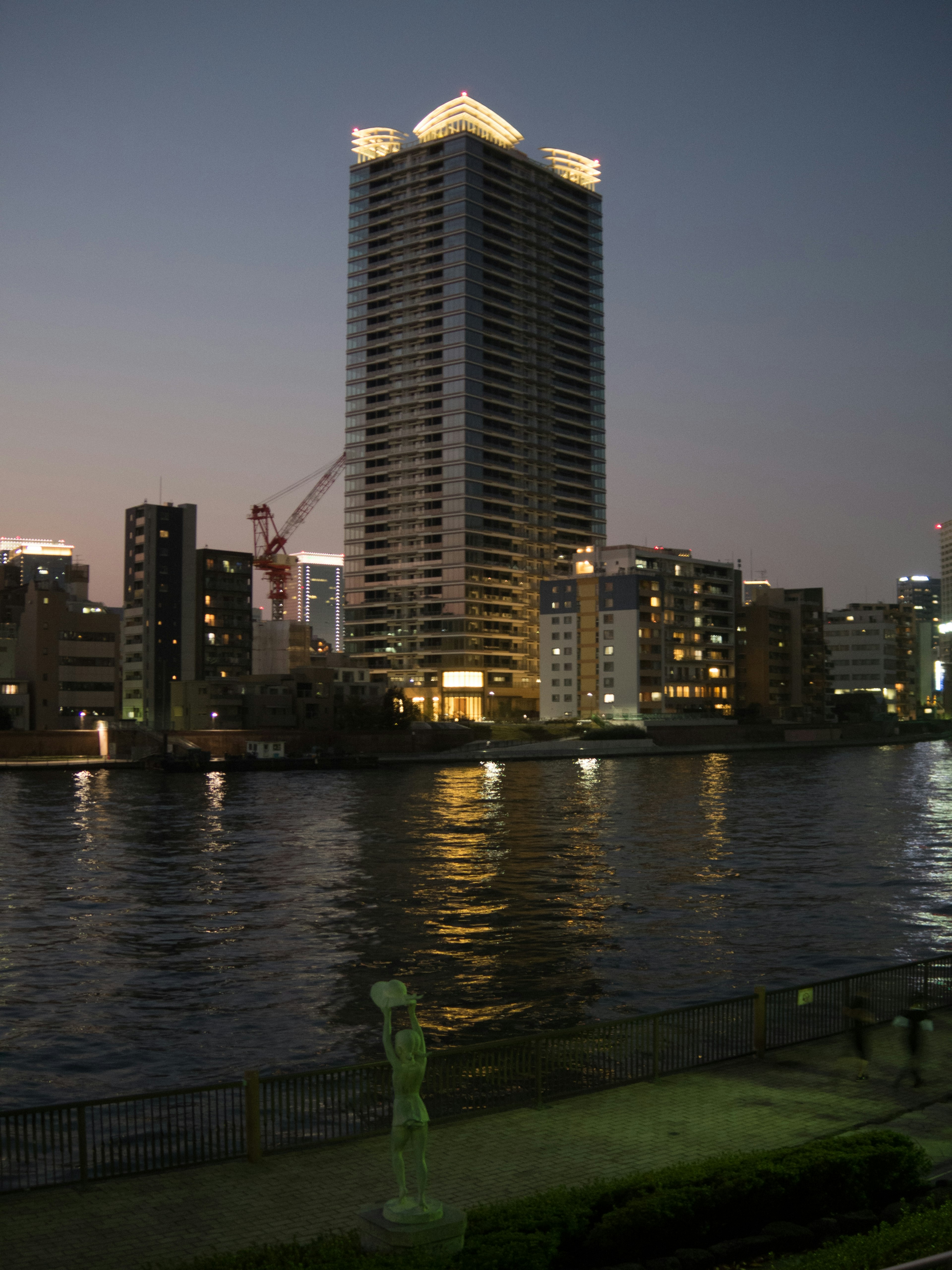 夜の川沿いに立つ高層ビルと周囲の都市景観