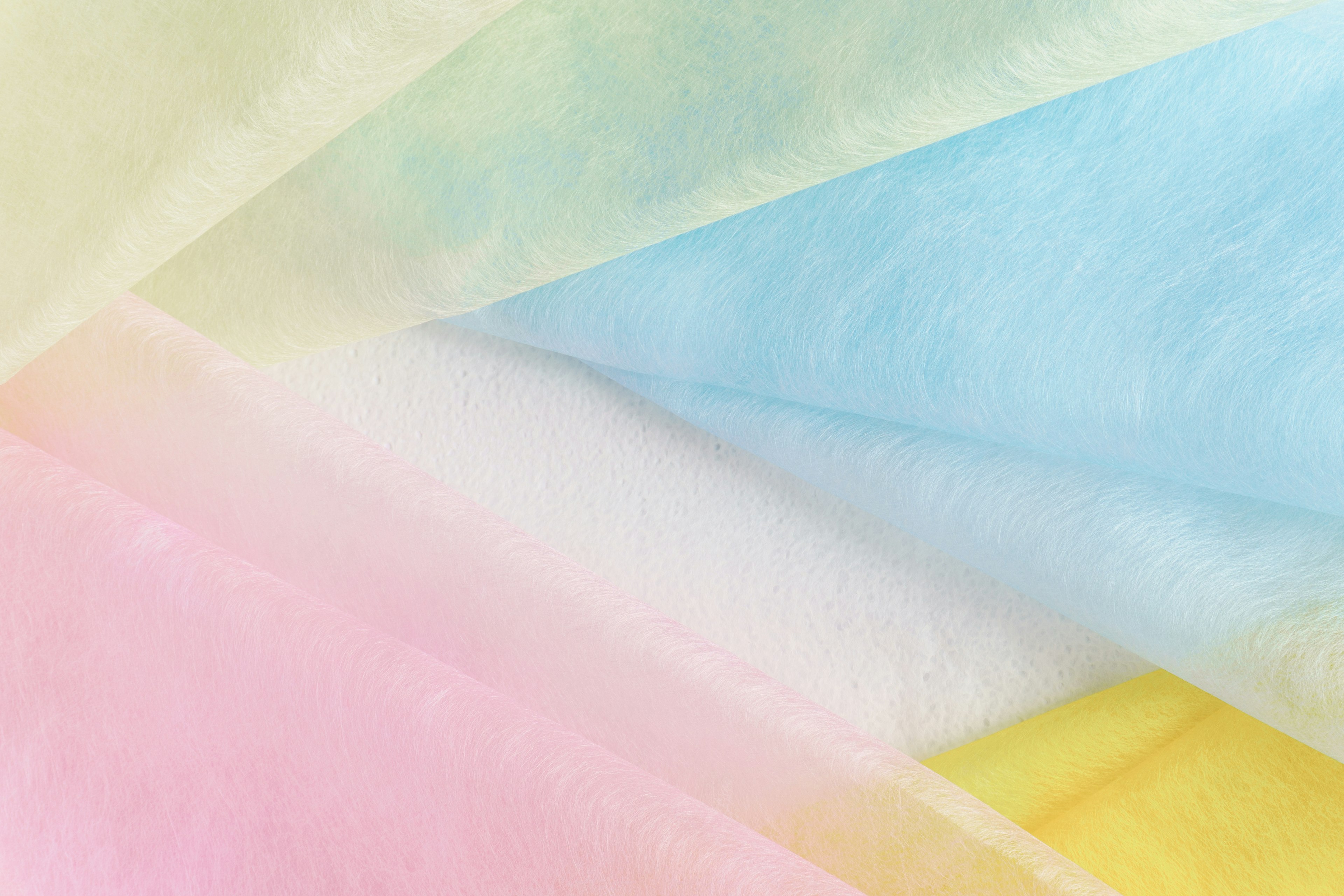 Image of overlapping soft-colored fabrics featuring yellow, blue, white, and pink