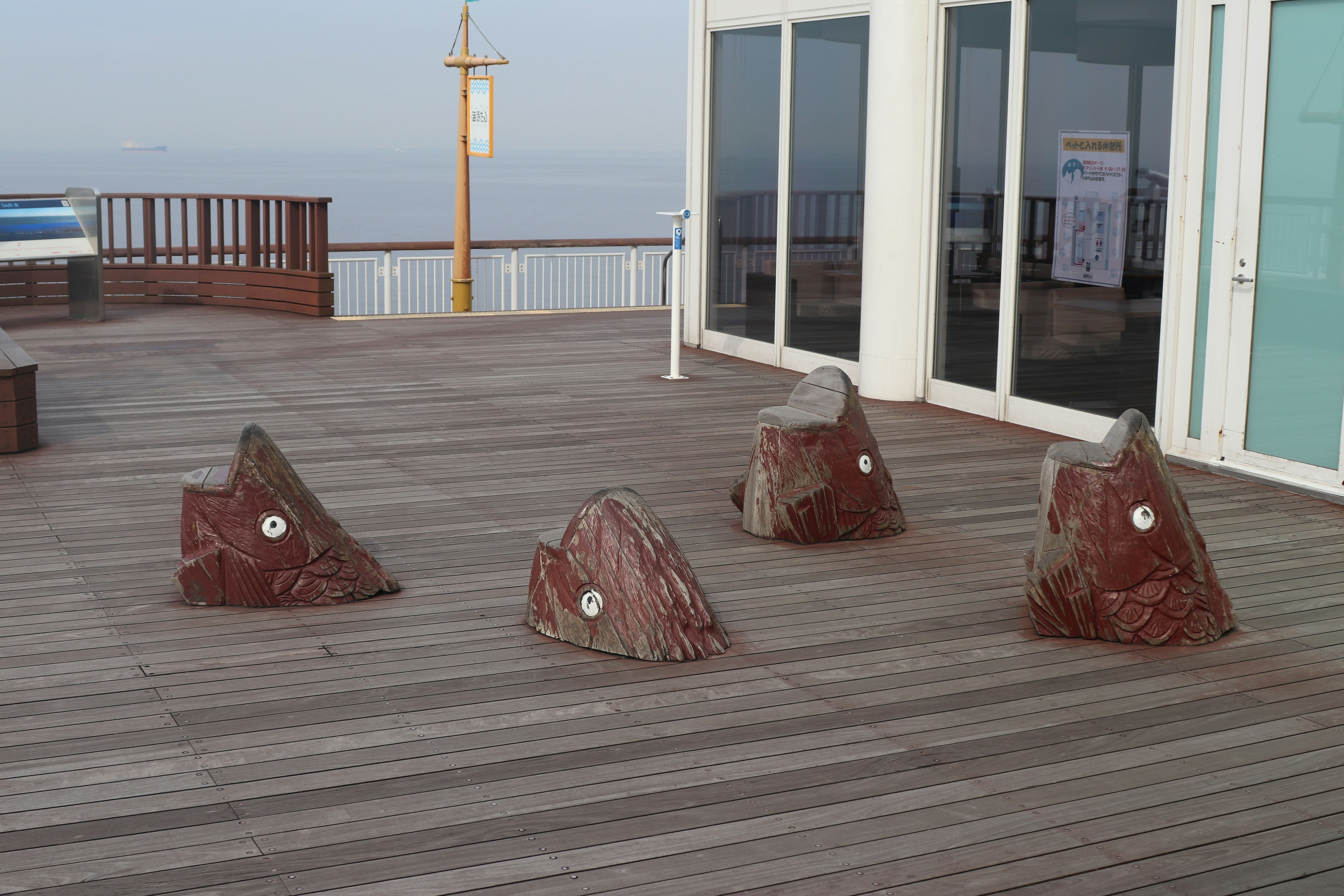 Four rock sculptures on an outdoor deck near a glass wall