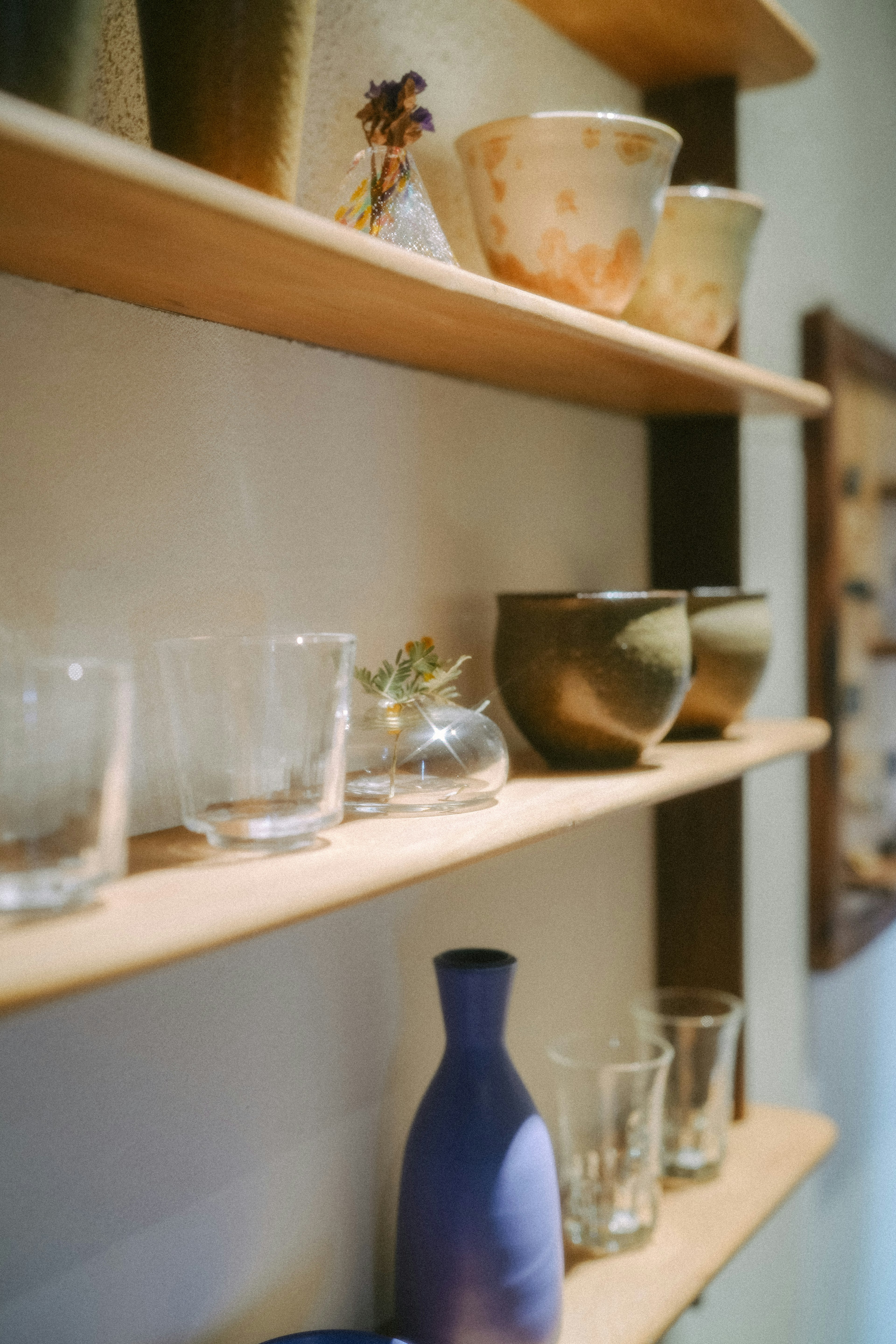 Wooden shelves displaying glass and ceramic dishes and vases