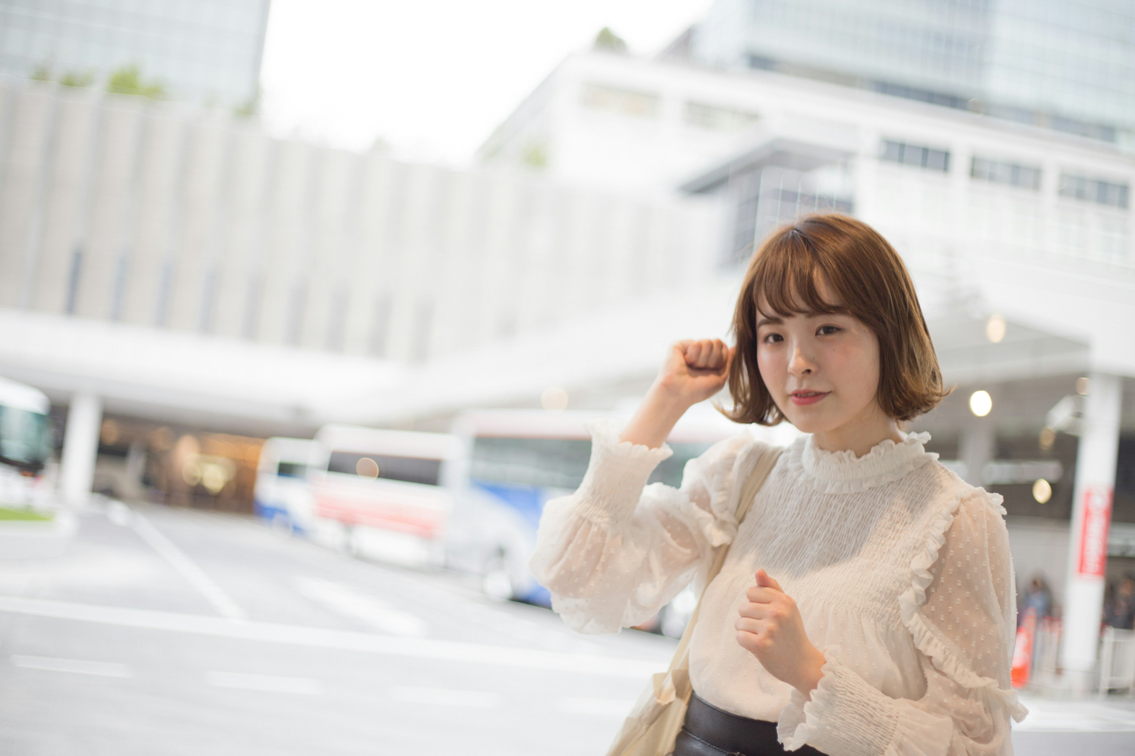 A young woman wearing a white blouse standing in an urban setting