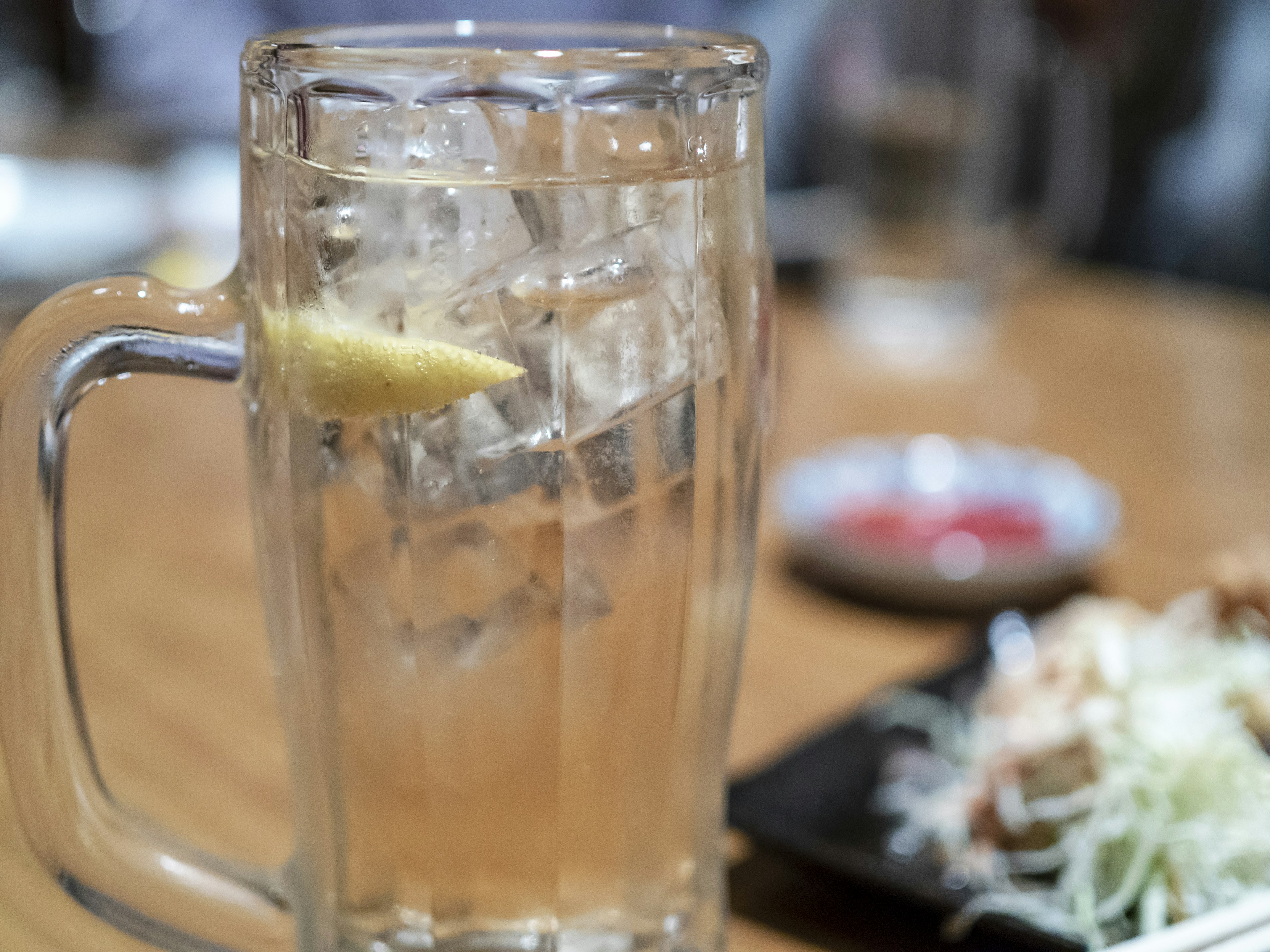 Vaso de bebida de limón con hielo y ensalada en un plato