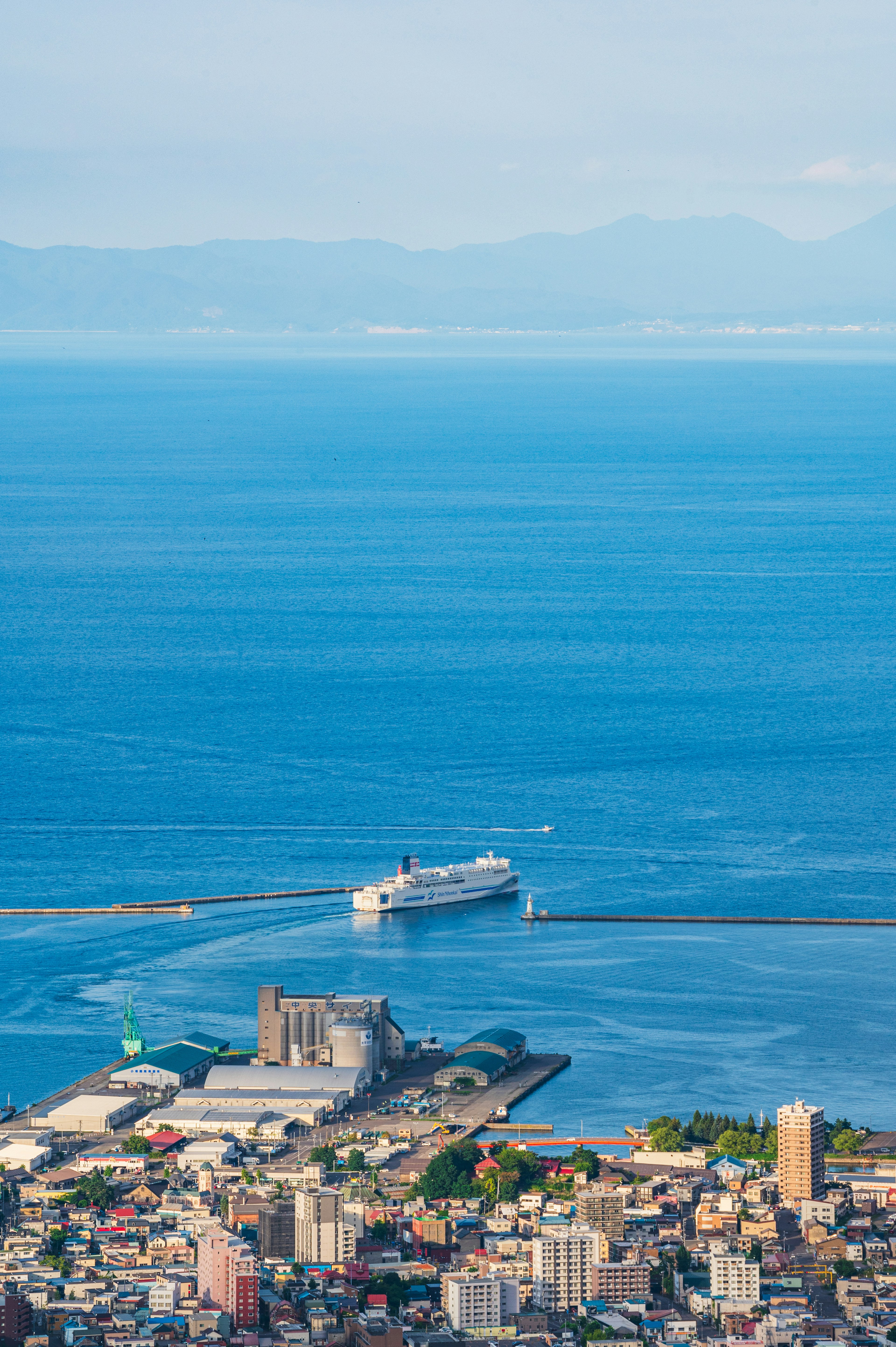 Fähre, die in einen Hafen mit blauem Meer und Stadtlandschaft im Hintergrund einläuft