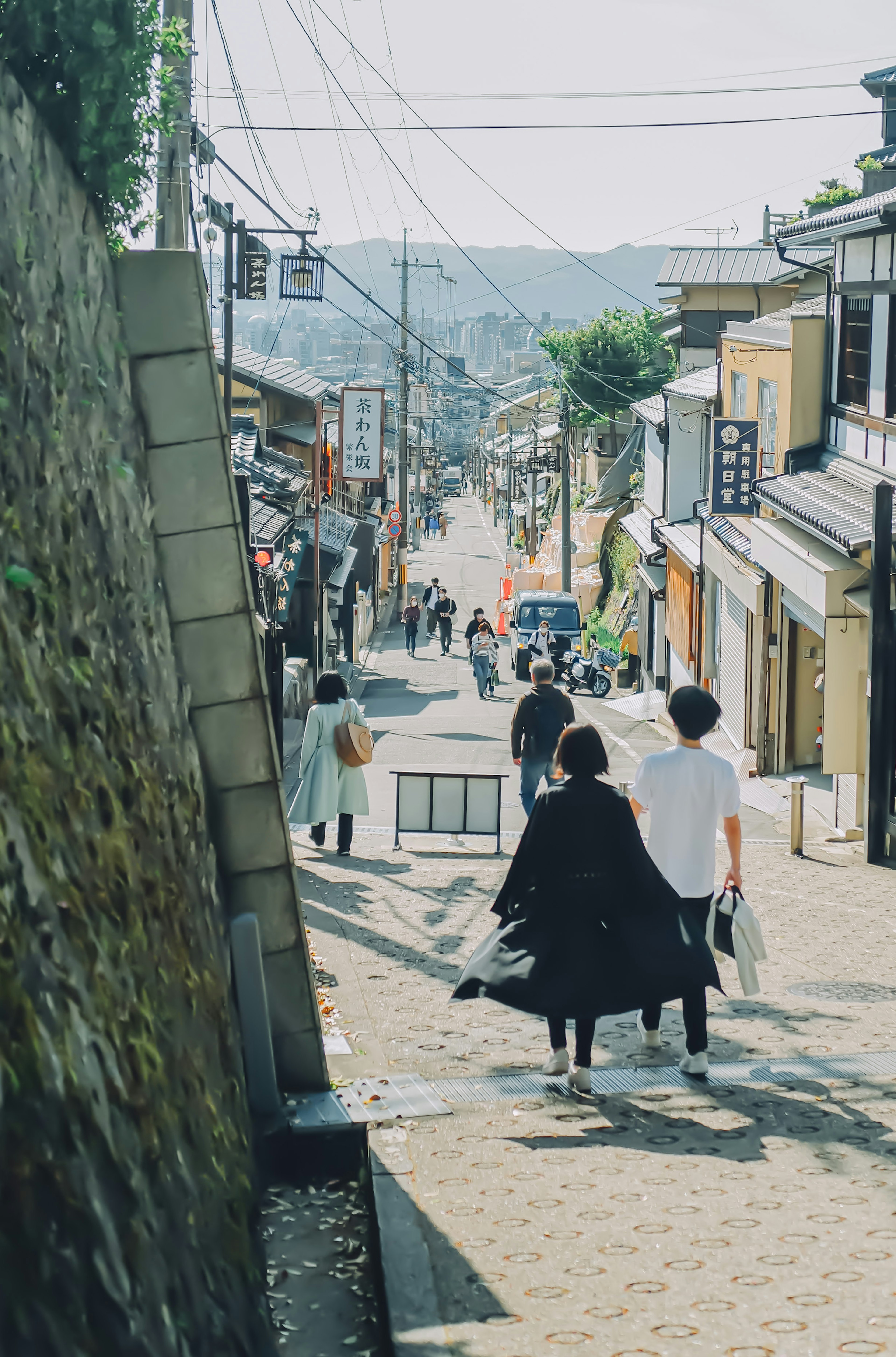 People walking down a sloped street with traditional buildings