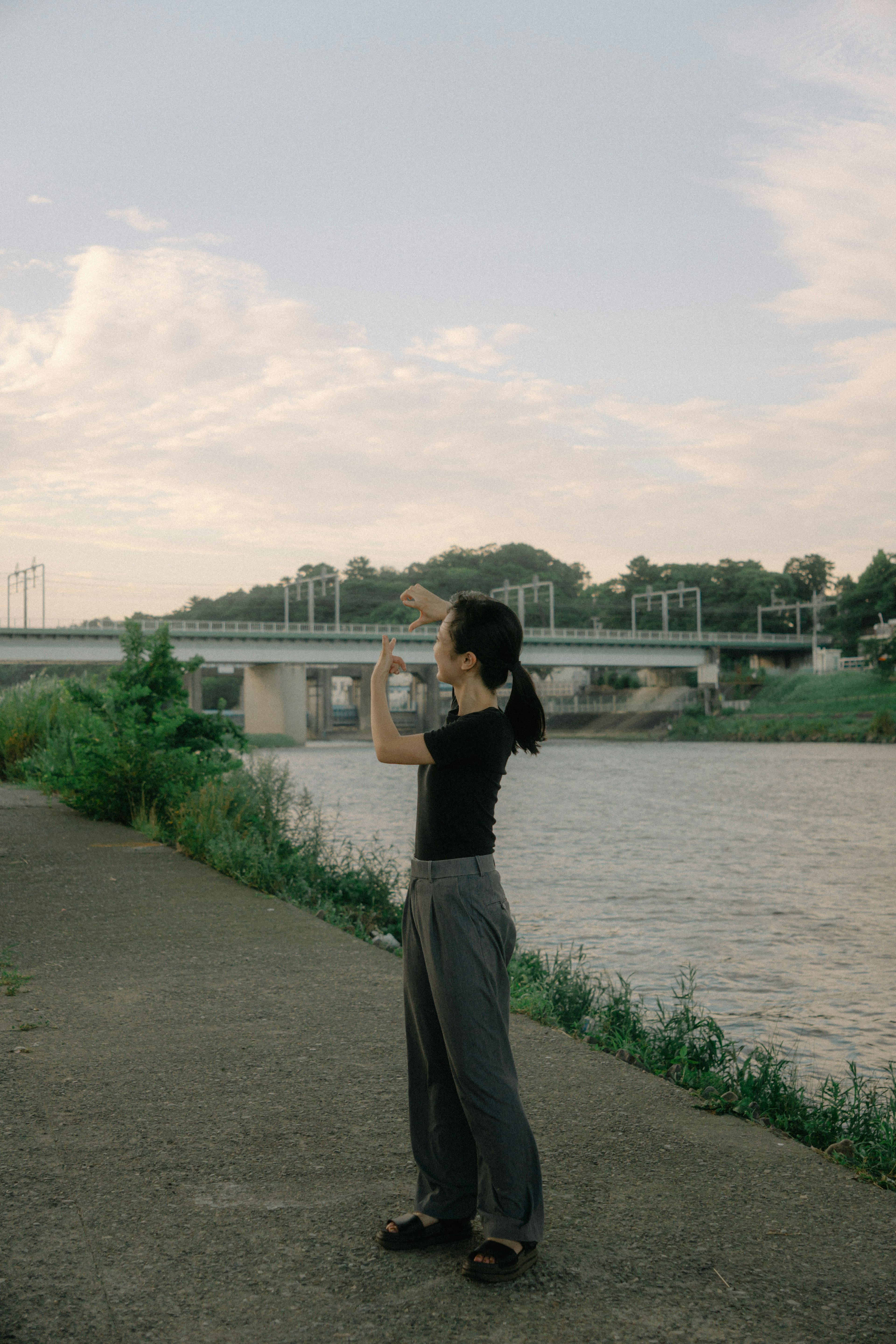 川辺でカメラを構える女性と橋の風景