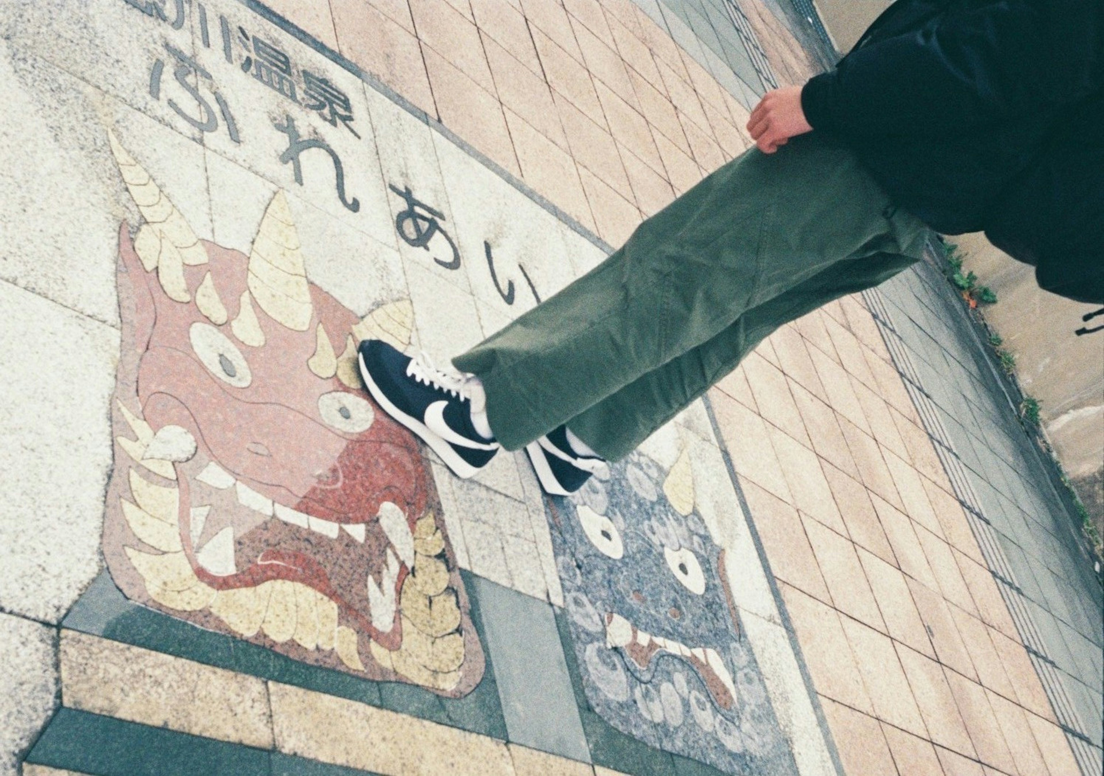 A person standing on tiles featuring red and blue demon faces on the ground