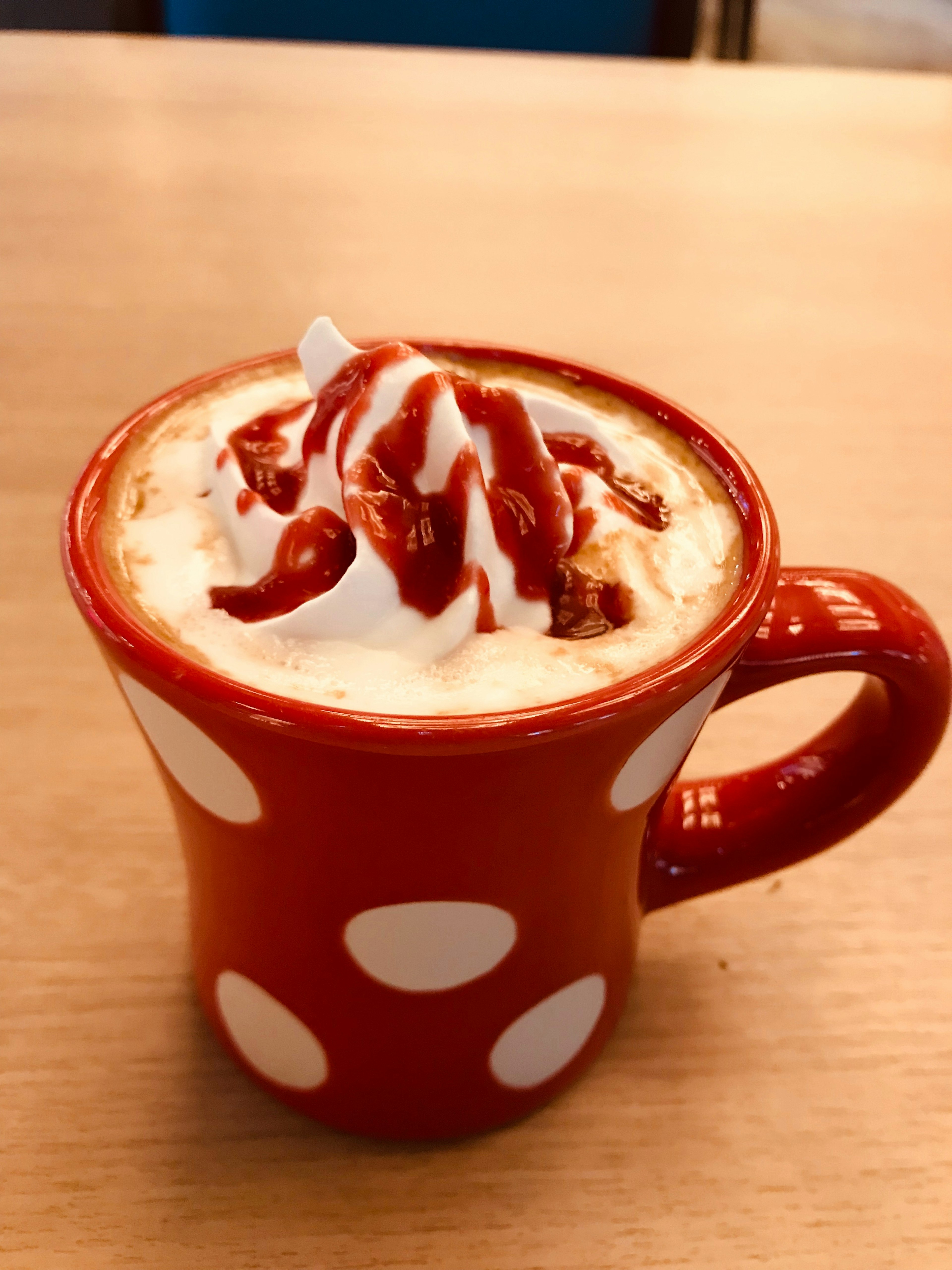 Taza roja con puntos llena de café con crema batida y salsa