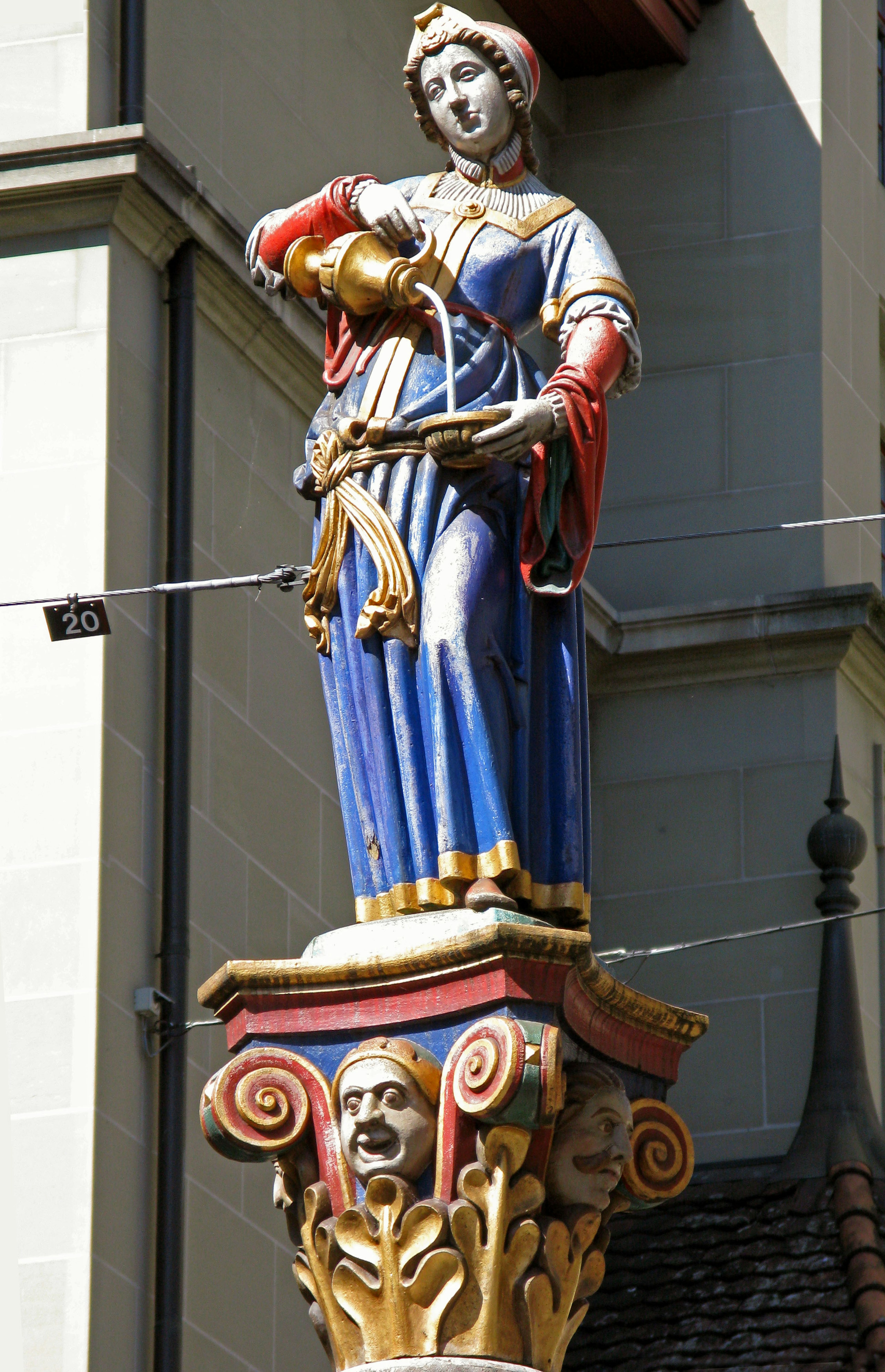 Eine schöne weibliche Statue in einem blauen Kleid, die Wasser gießt