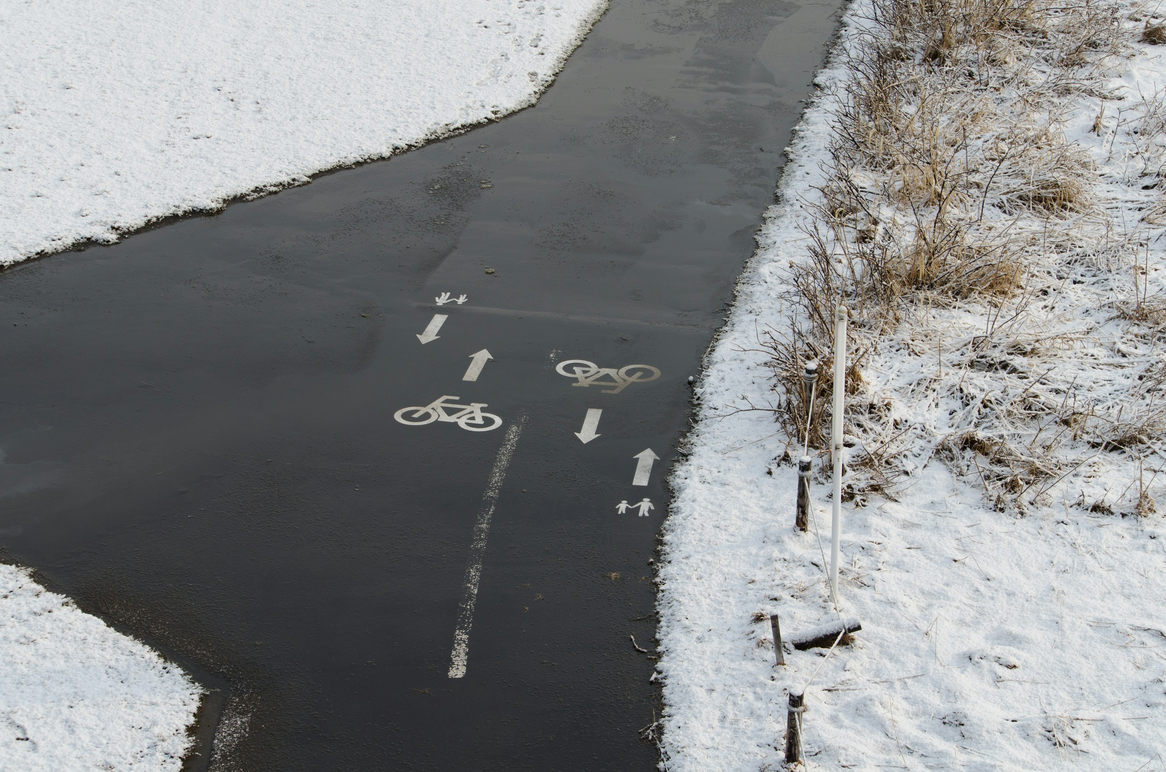 Fahrradweg mit Fahrradsymbolen auf einem verschneiten Weg