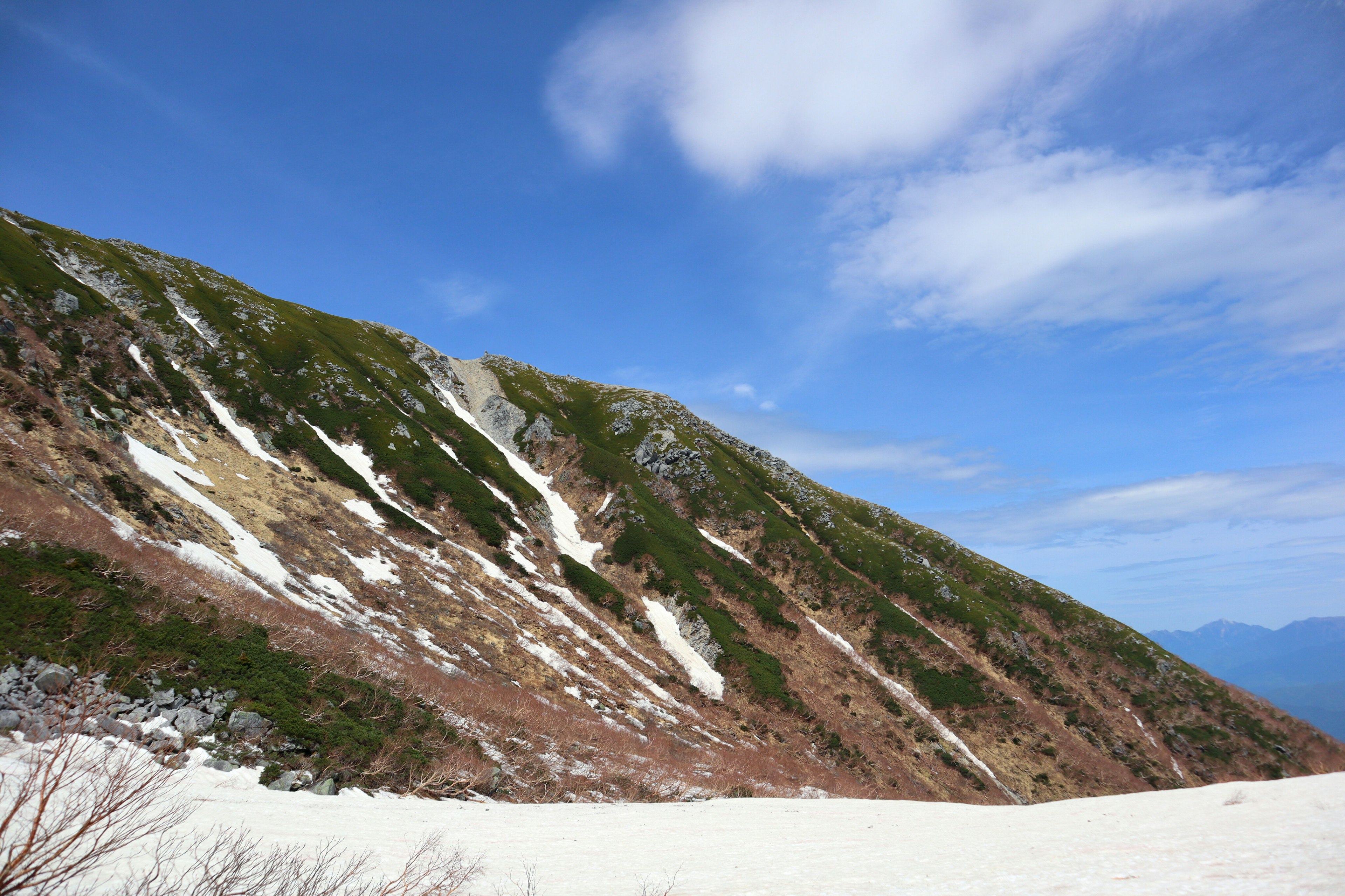 Schneebedeckte Bergseite mit blauem Himmel