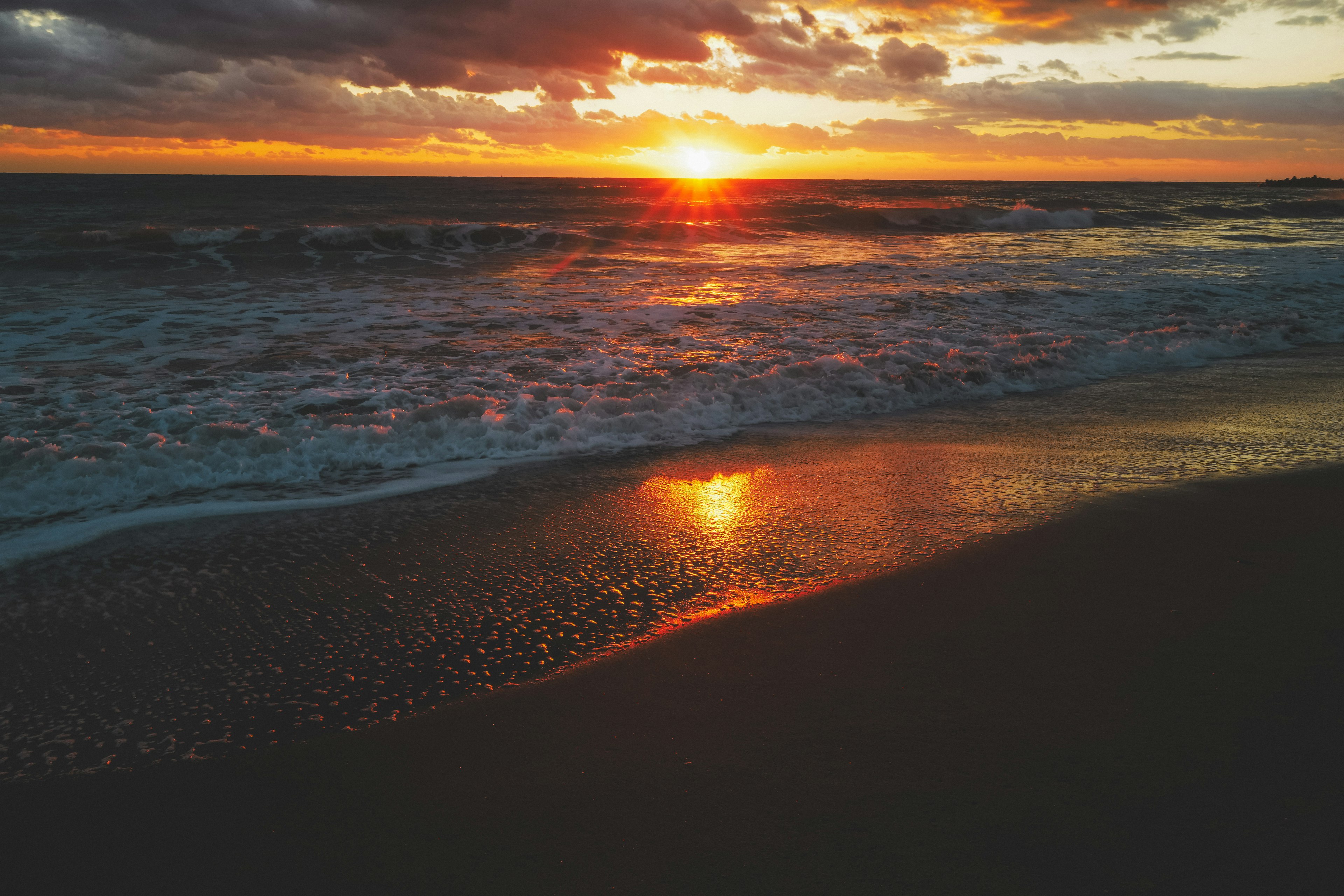 夕日が海に沈む様子を捉えたビーチの風景