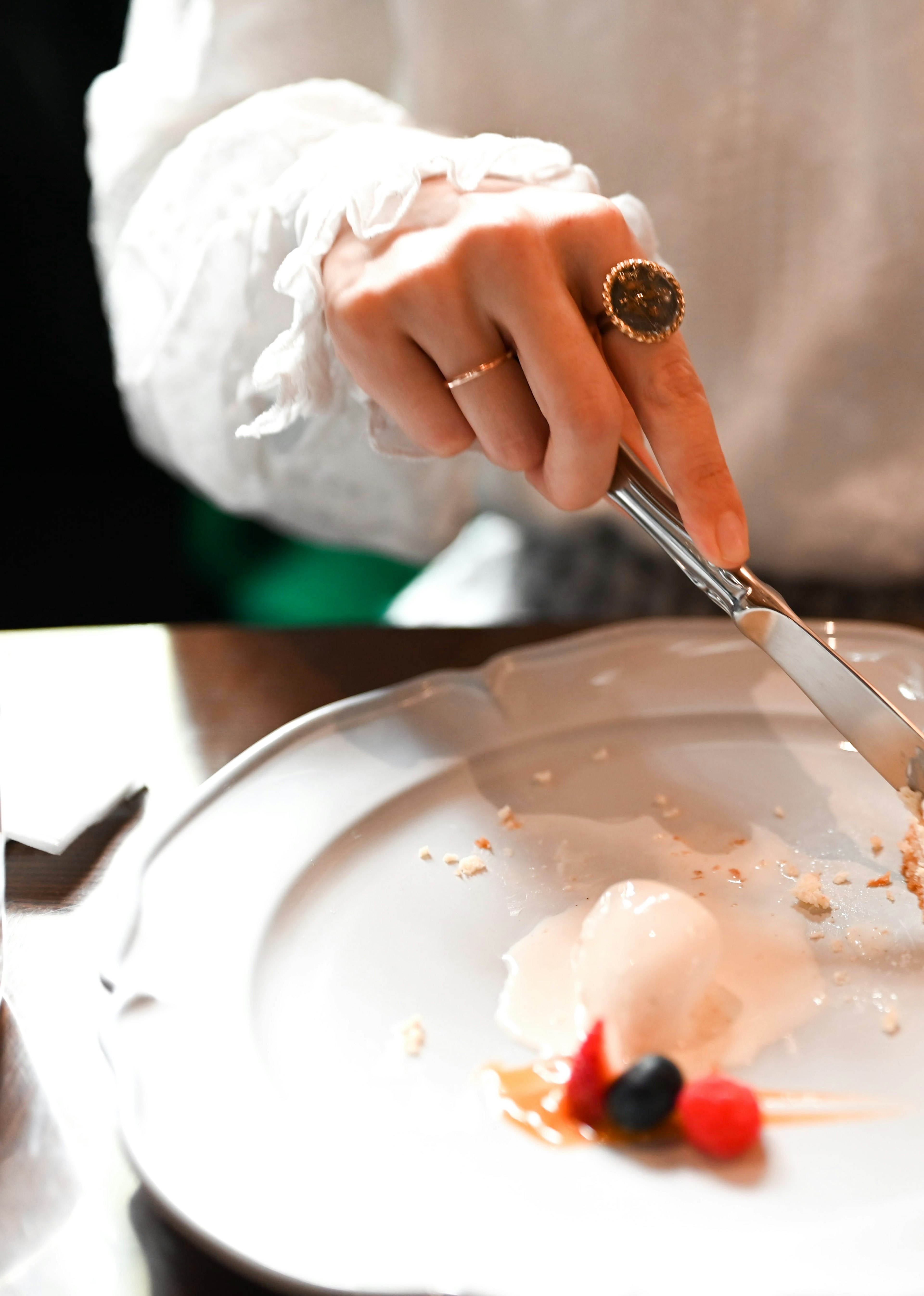 Una mano con una camisa blanca cortando un postre en un plato