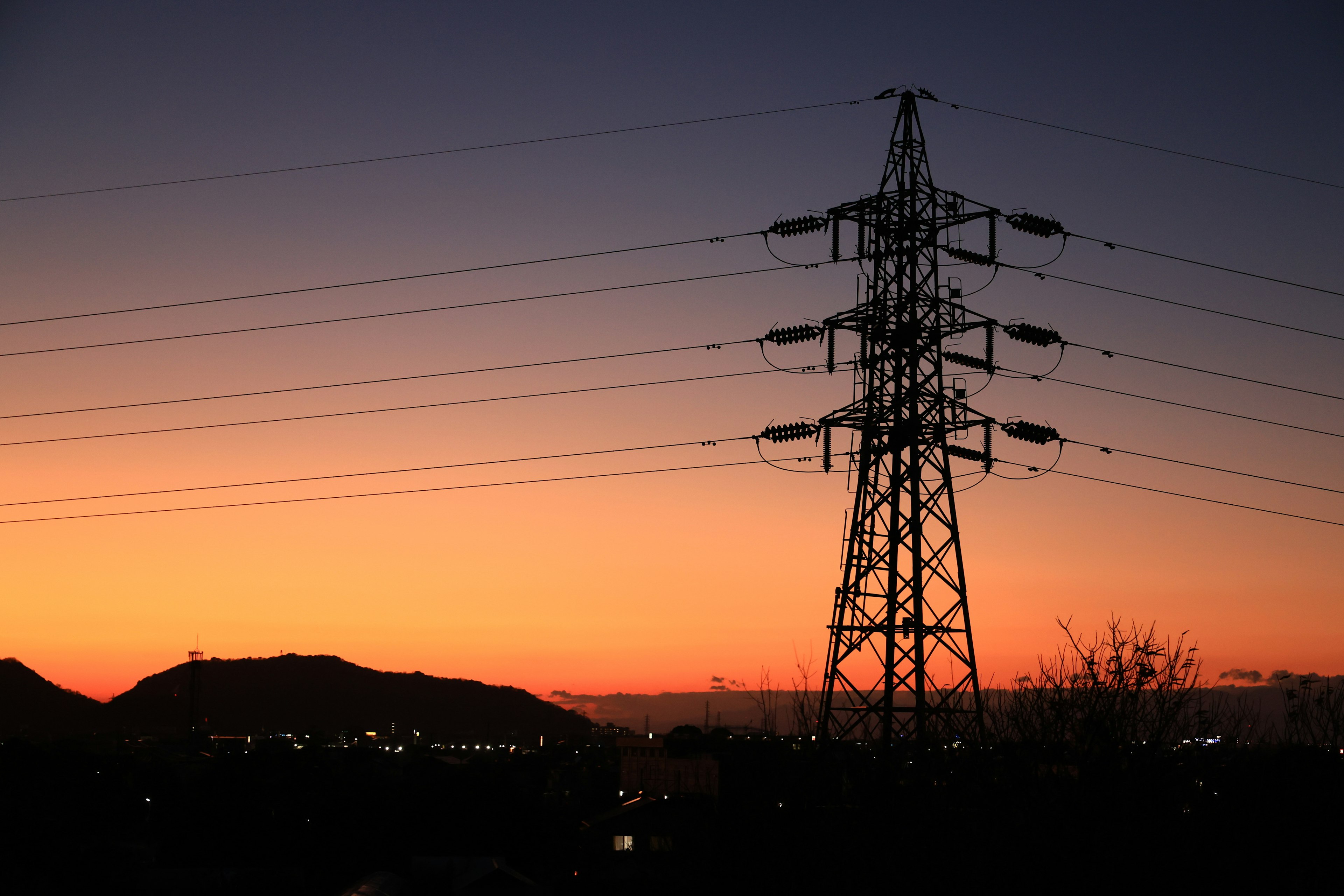 Silhouette of a power tower against a colorful sunset sky