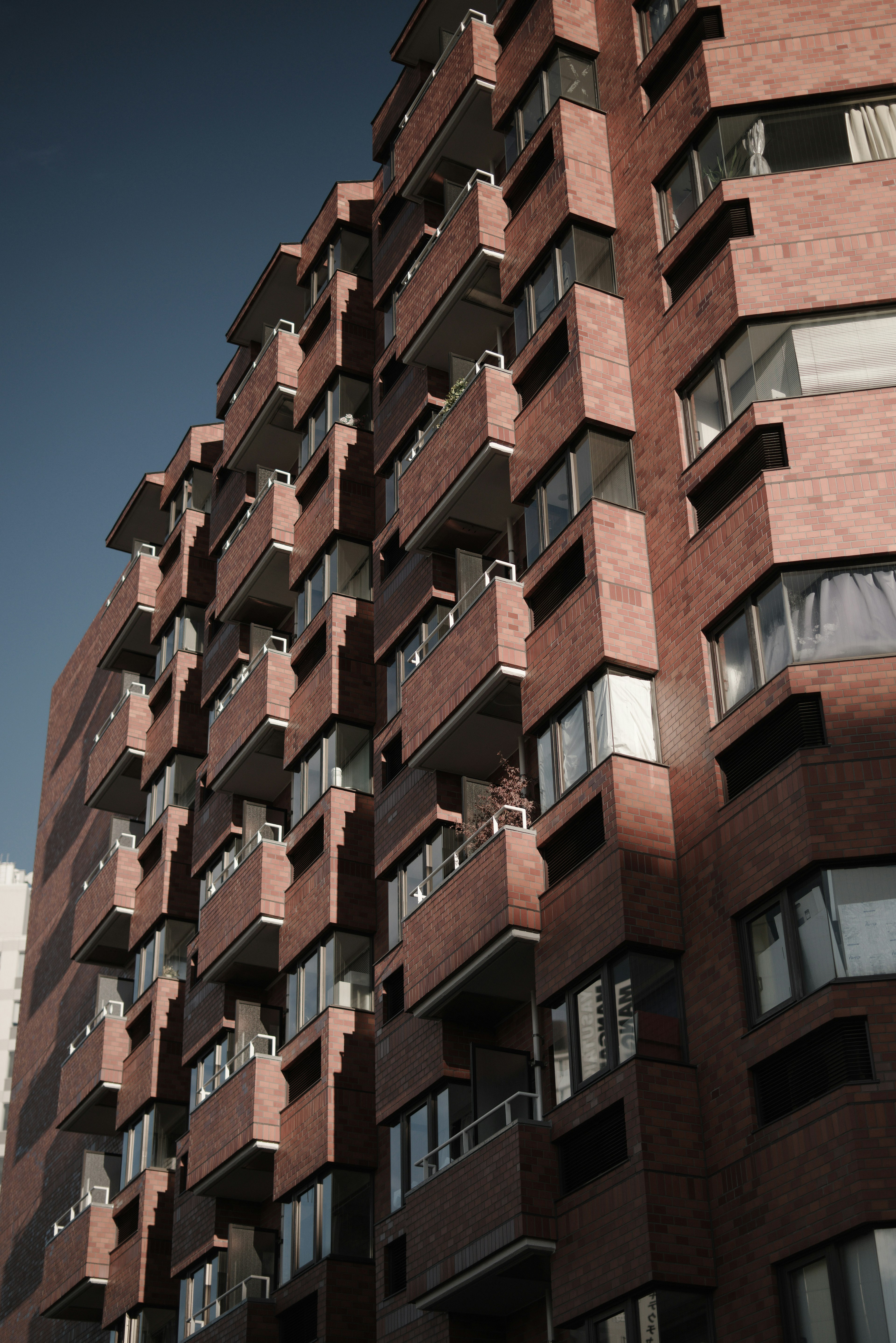 Side view of an apartment building with reddish-brown exterior and balconies